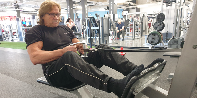 68-vuotias lihaksikas mies treenaamassa kuntosalilla voimaharjoittelua
