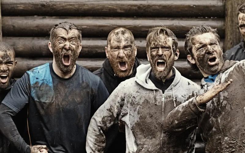 En grupp maskulina män, täckta av lera