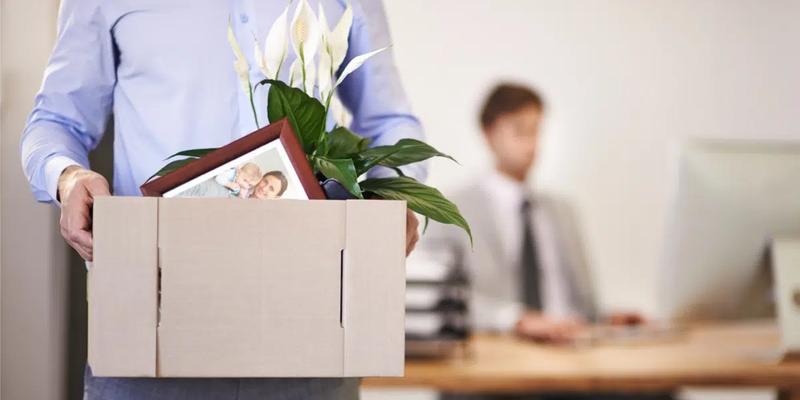 Irtisanottu mies kantaa toimistolta pahvilaatikossa henkilökohtaisia tavaroitaan