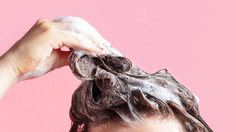 En kvinna tvättar håret med ett volymschampo