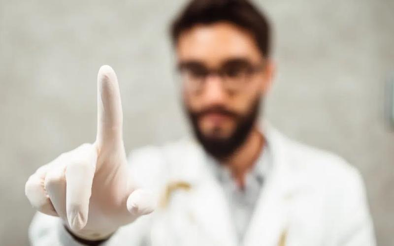 Læge med hvid gummihandske, som holder pegefingeren frem for at foretage en prostata-undersøgelse