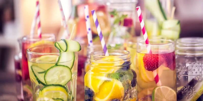 Vattenglas som har dekorerats med läckra skivor av frukt, grönsaker och dekorerade med sugrör