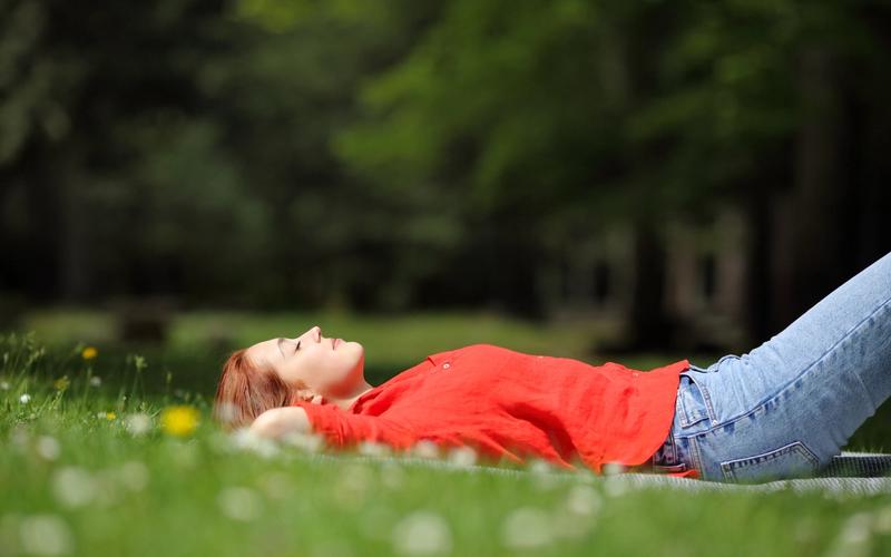 Træt kvinde hviler sig i græsset om foråret