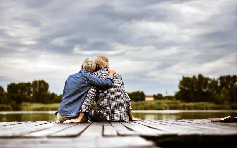 Ældre par som sidder på en bro og omfavner hinanden