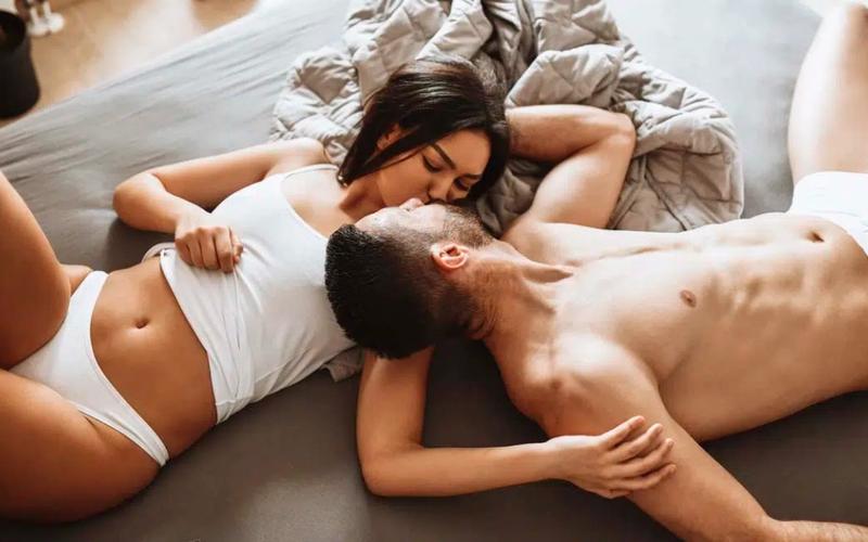 Mies ja nainen suutelevat sängyllä alusvaatteissa