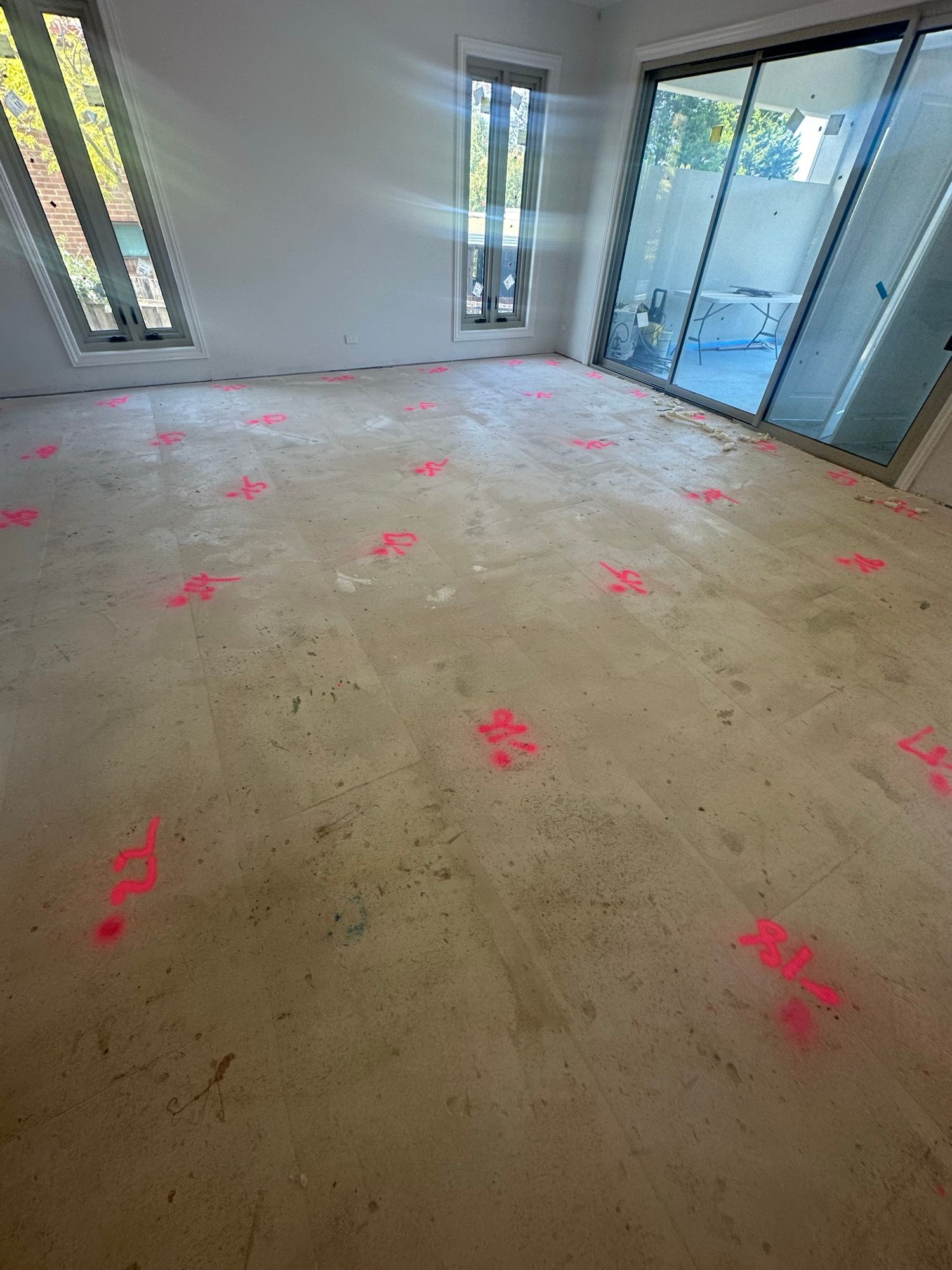 Whole-home concrete subfloor marked with measured high and low points before self-levelling preparation.