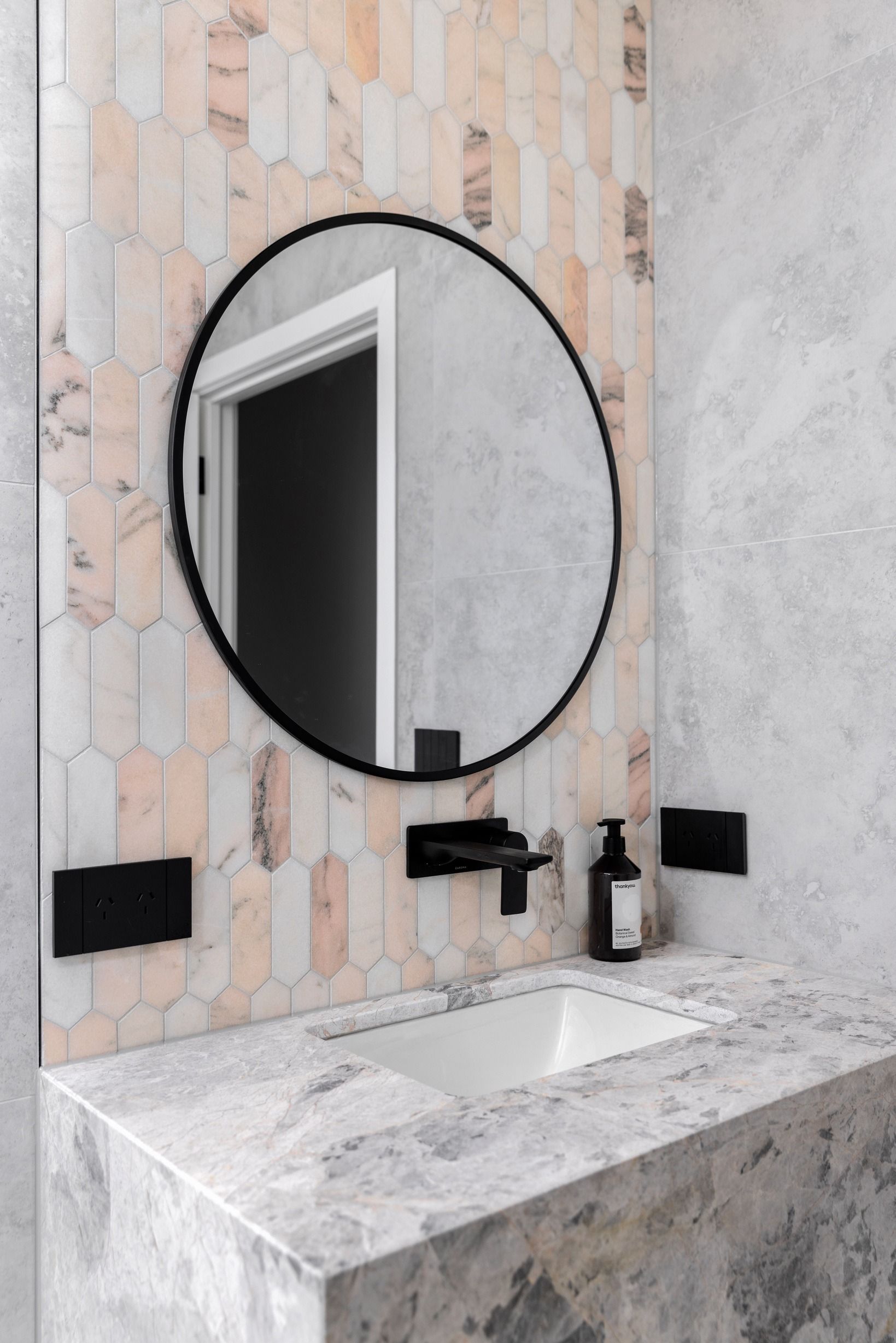 Stone vanity and round mirror in a Glen Iris powder room.