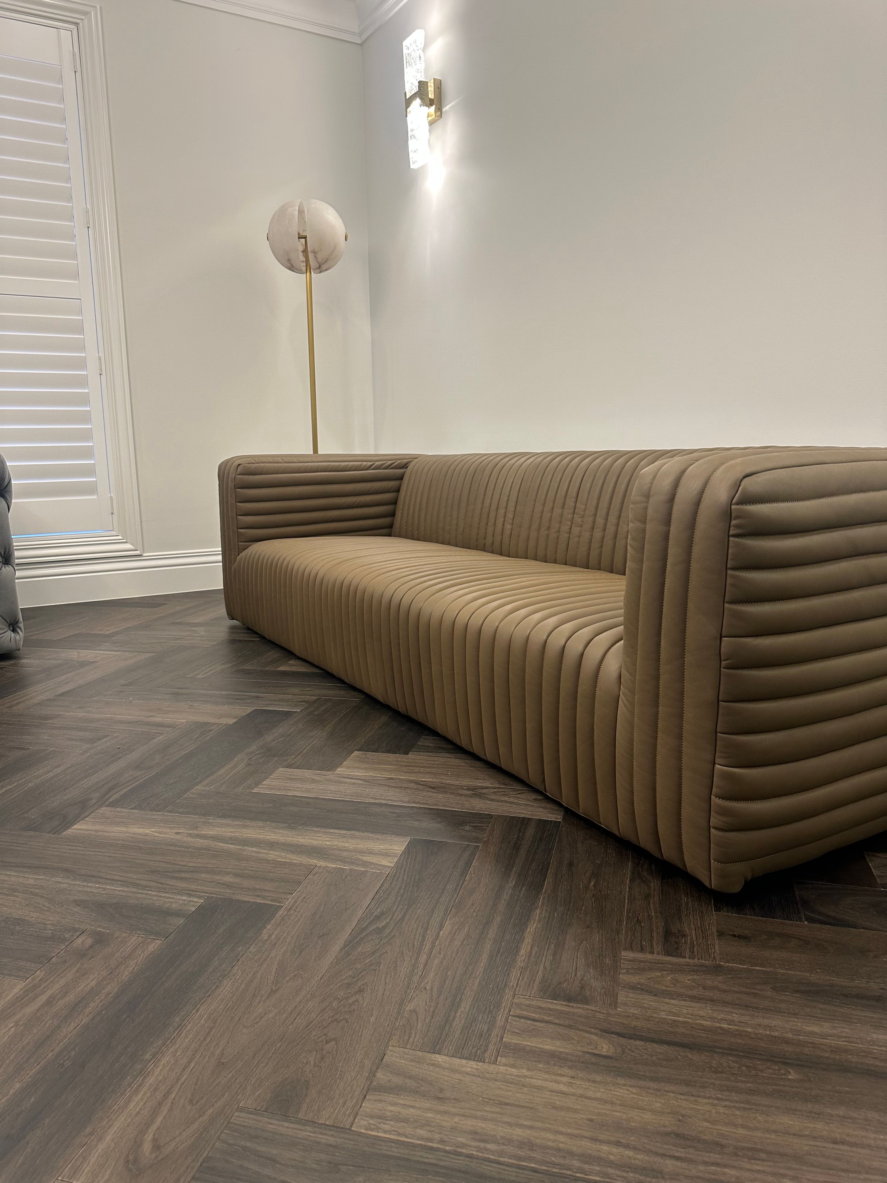 Ash Grey herringbone flooring beside a curved sofa in a Camberwell living room.