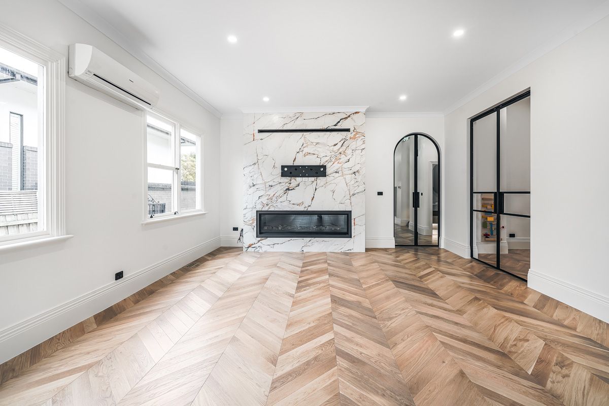 Champagne chevron flooring beside a marble fireplace in a Kew living room.