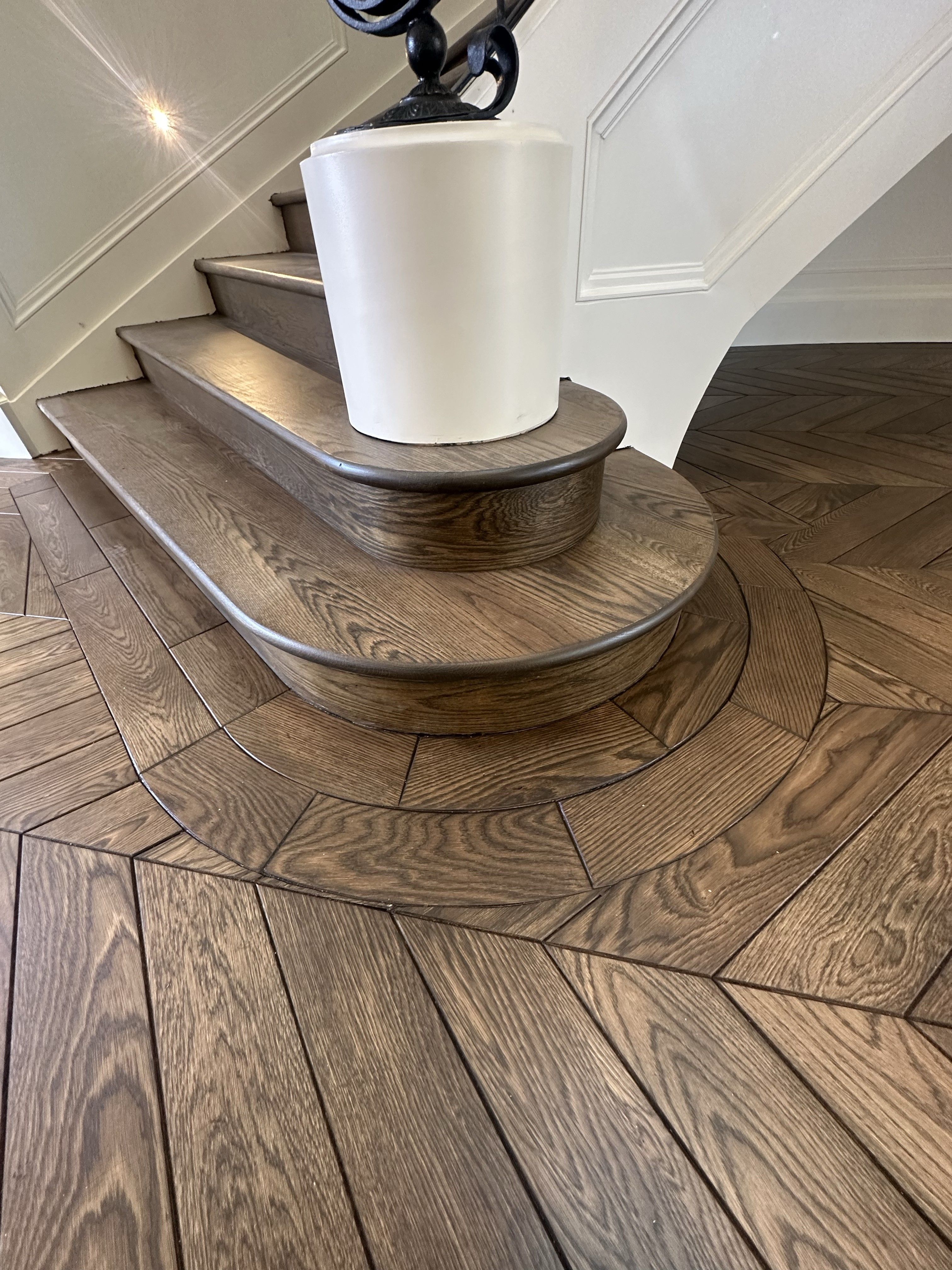 Solid oak chevron detailing around the curved staircase base.