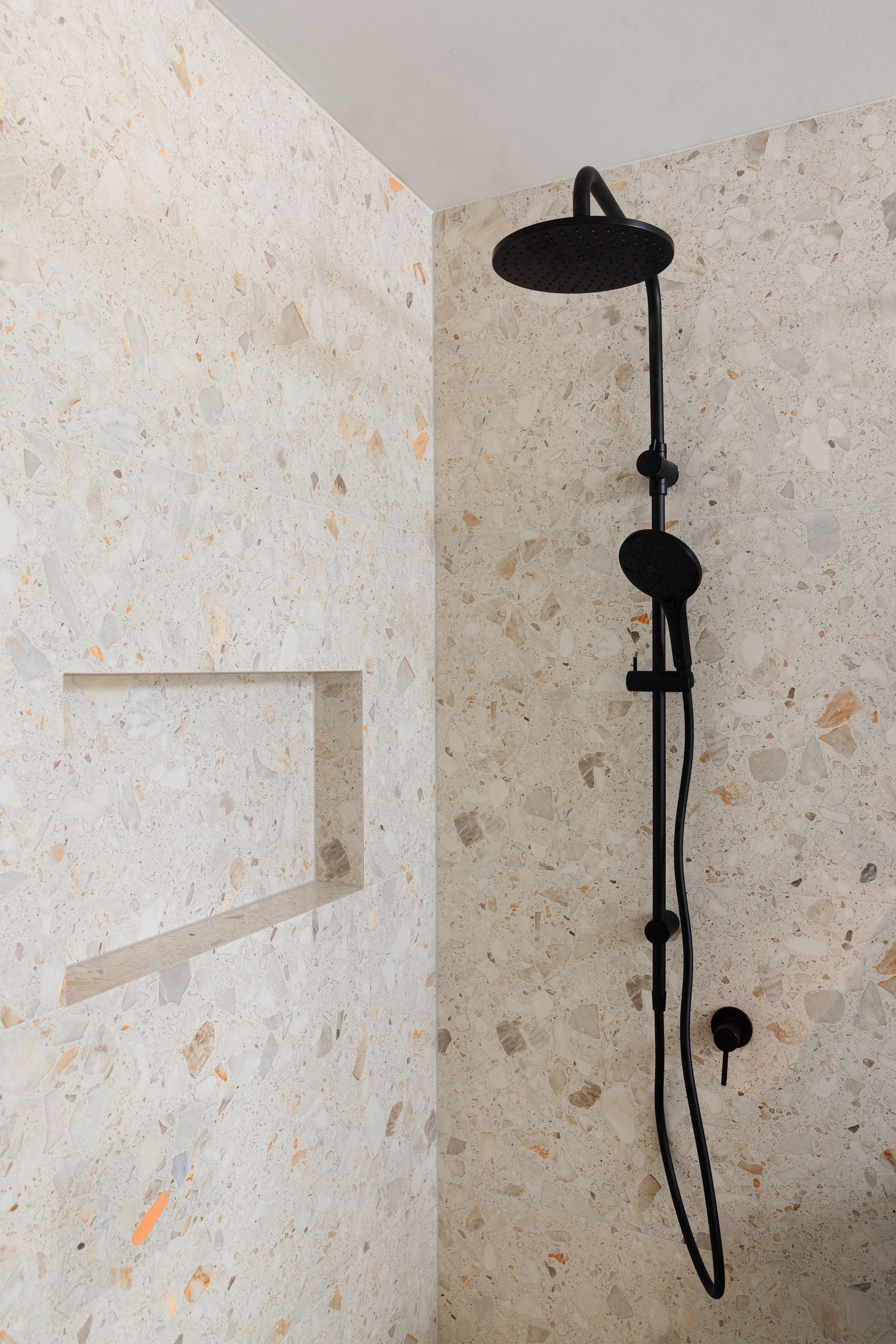 Black shower fixture against stone tiles in Wheelers Hill.
