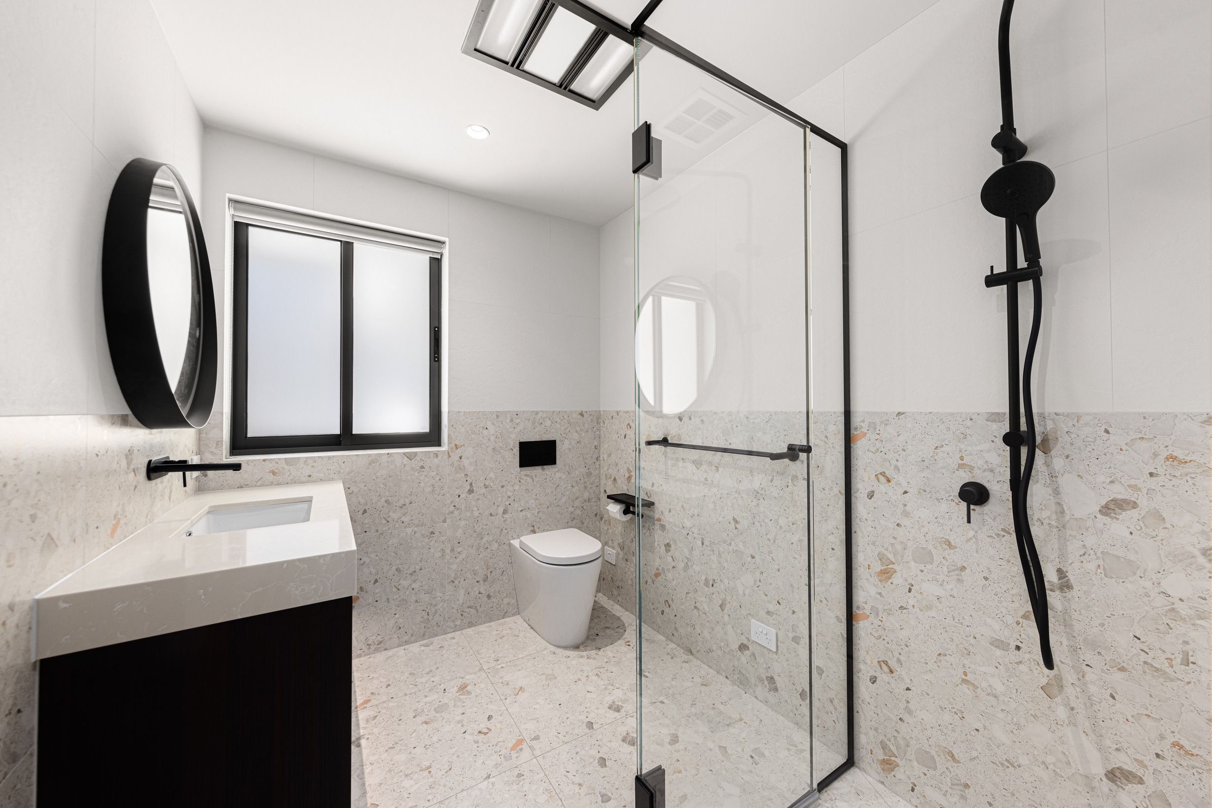 Black-framed shower and stone bathroom in the Wheelers Hill residence.