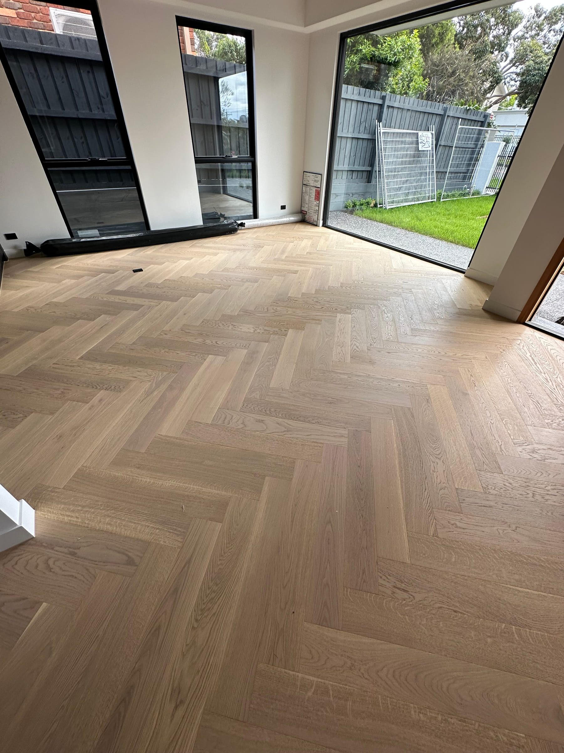 AB-grade oak herringbone flooring beside full-height windows in a Camberwell living room.