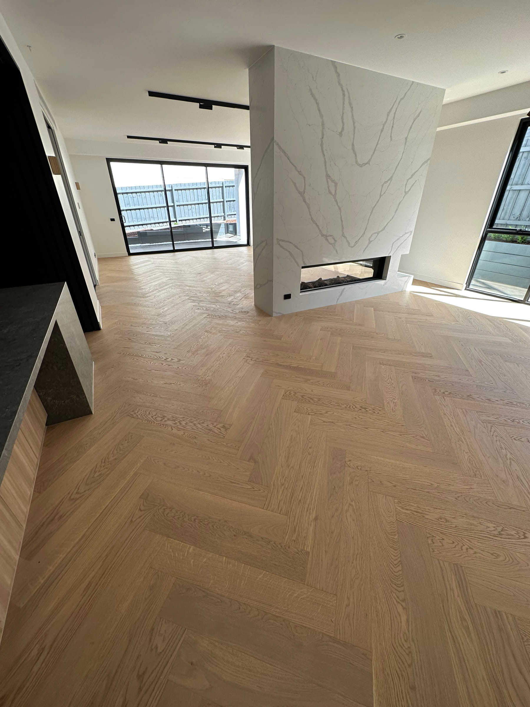 AB-grade engineered oak herringbone flooring across a Camberwell living area with a stone fireplace.