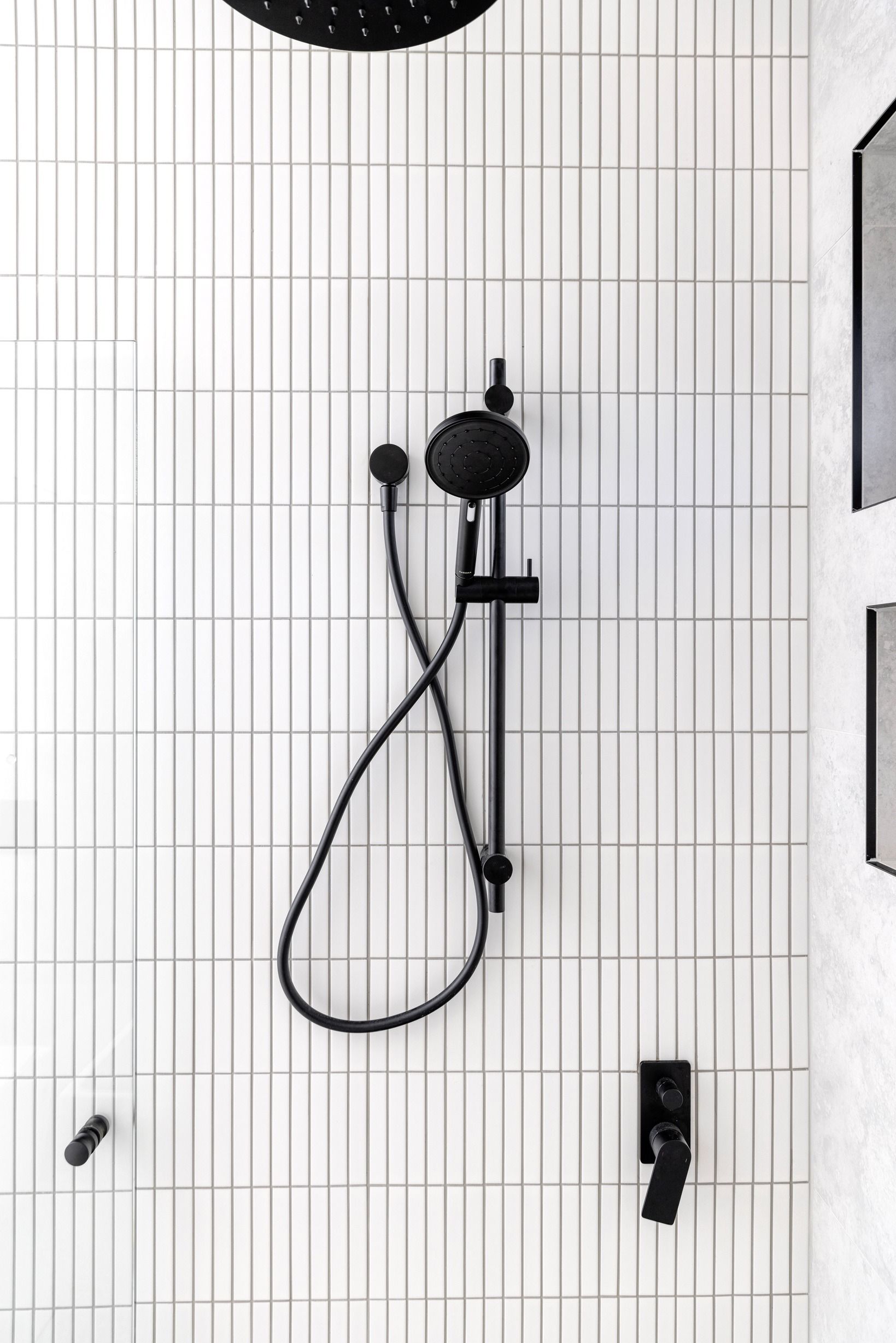 Black shower fitting against white tiles in the Glen Iris residence.