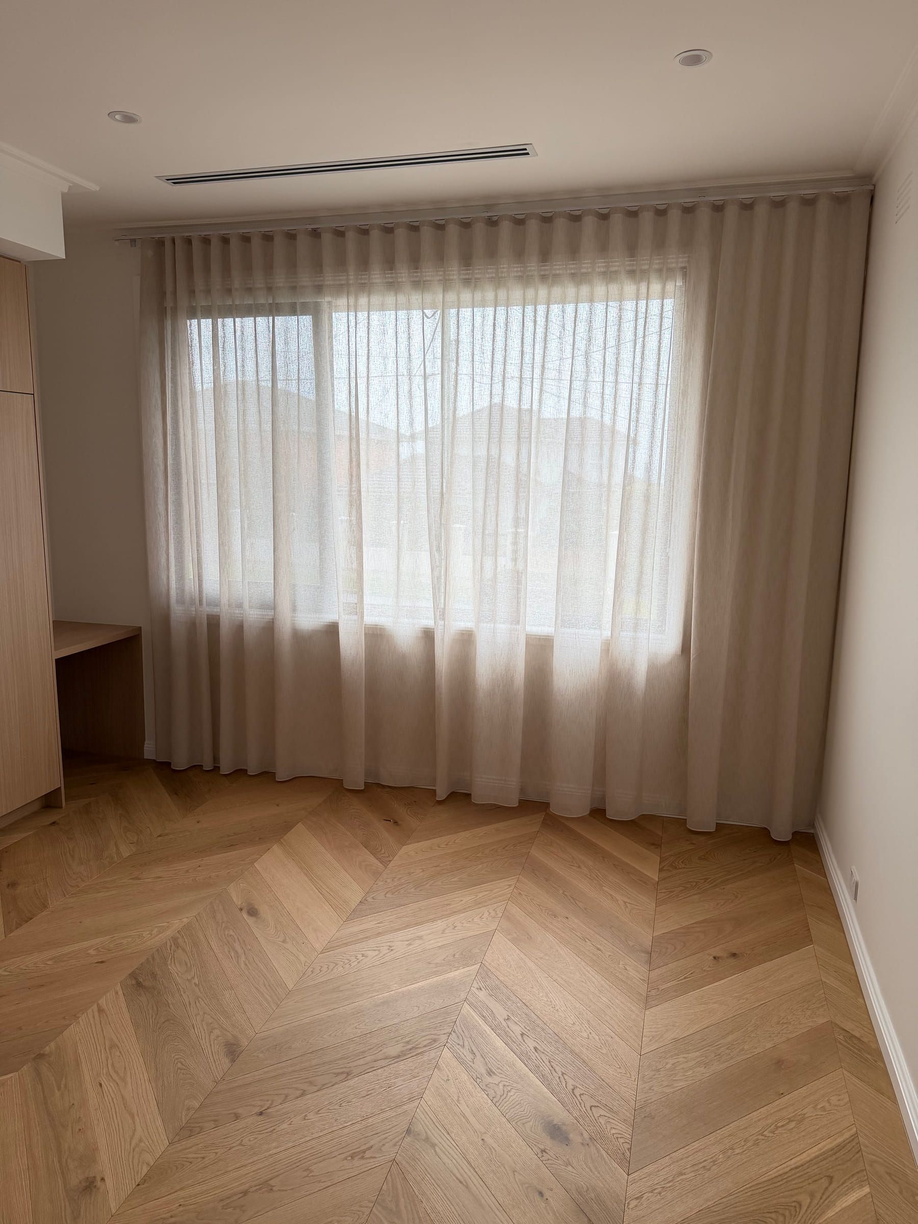 Natural Oak chevron flooring across a bright bedroom with full-width curtains in Bulleen.