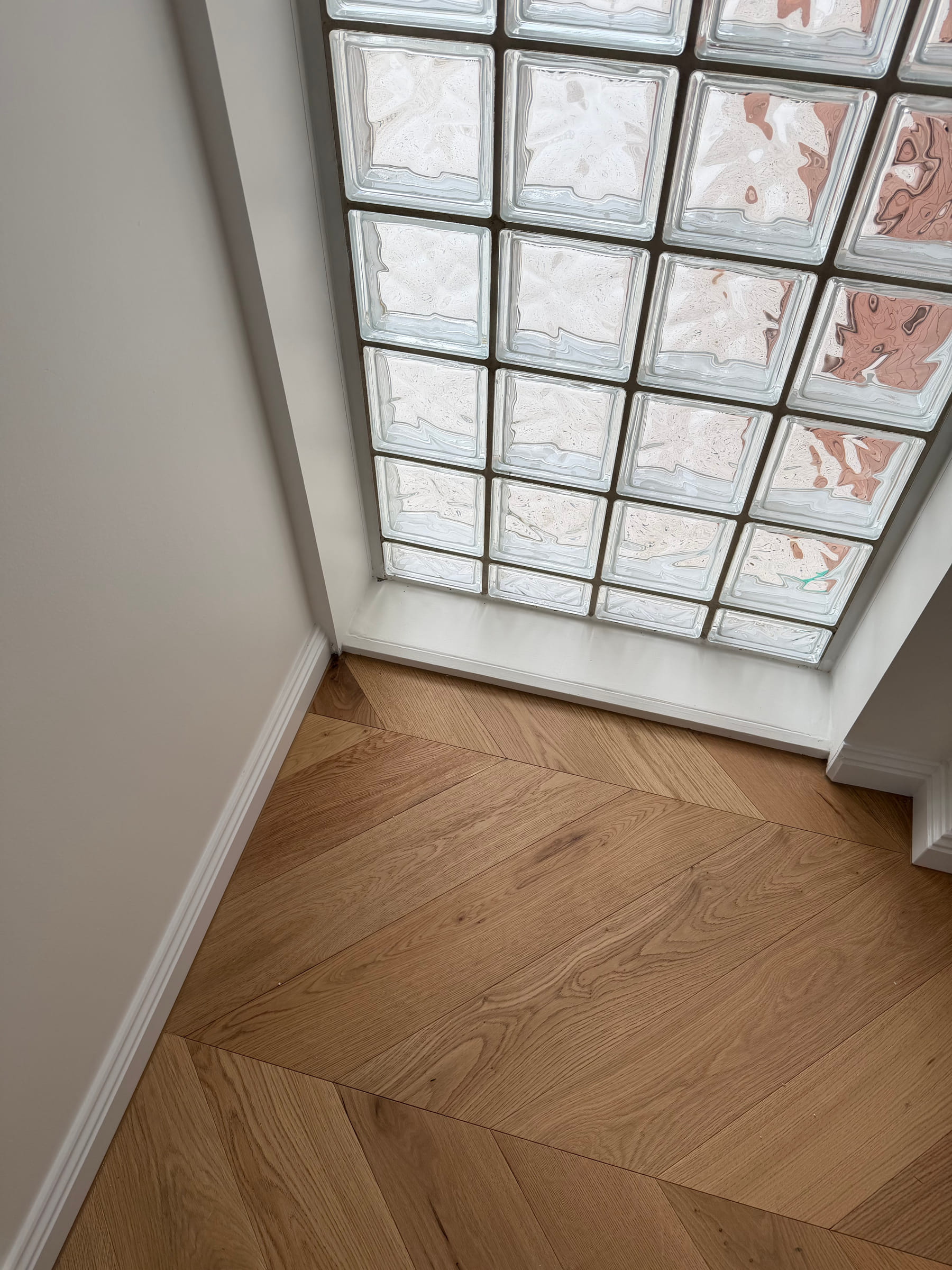 Chevron flooring detail beside a glass-block window in the Bulleen hallway.