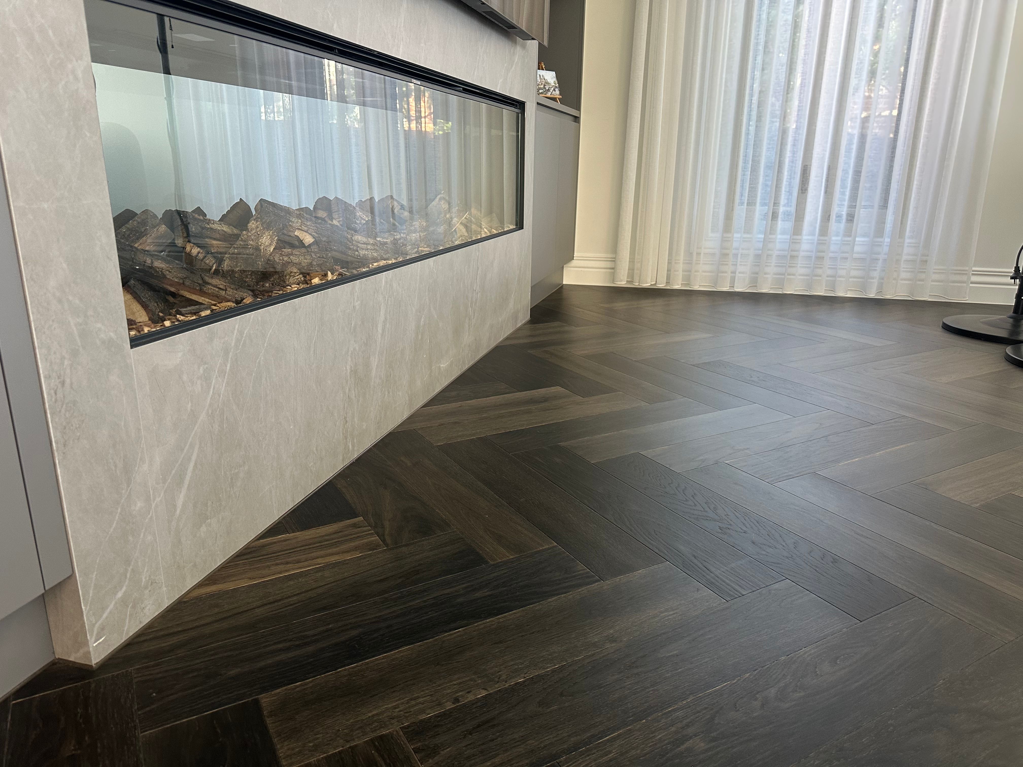 Ash Grey herringbone flooring detailed around a stone fireplace in Camberwell.