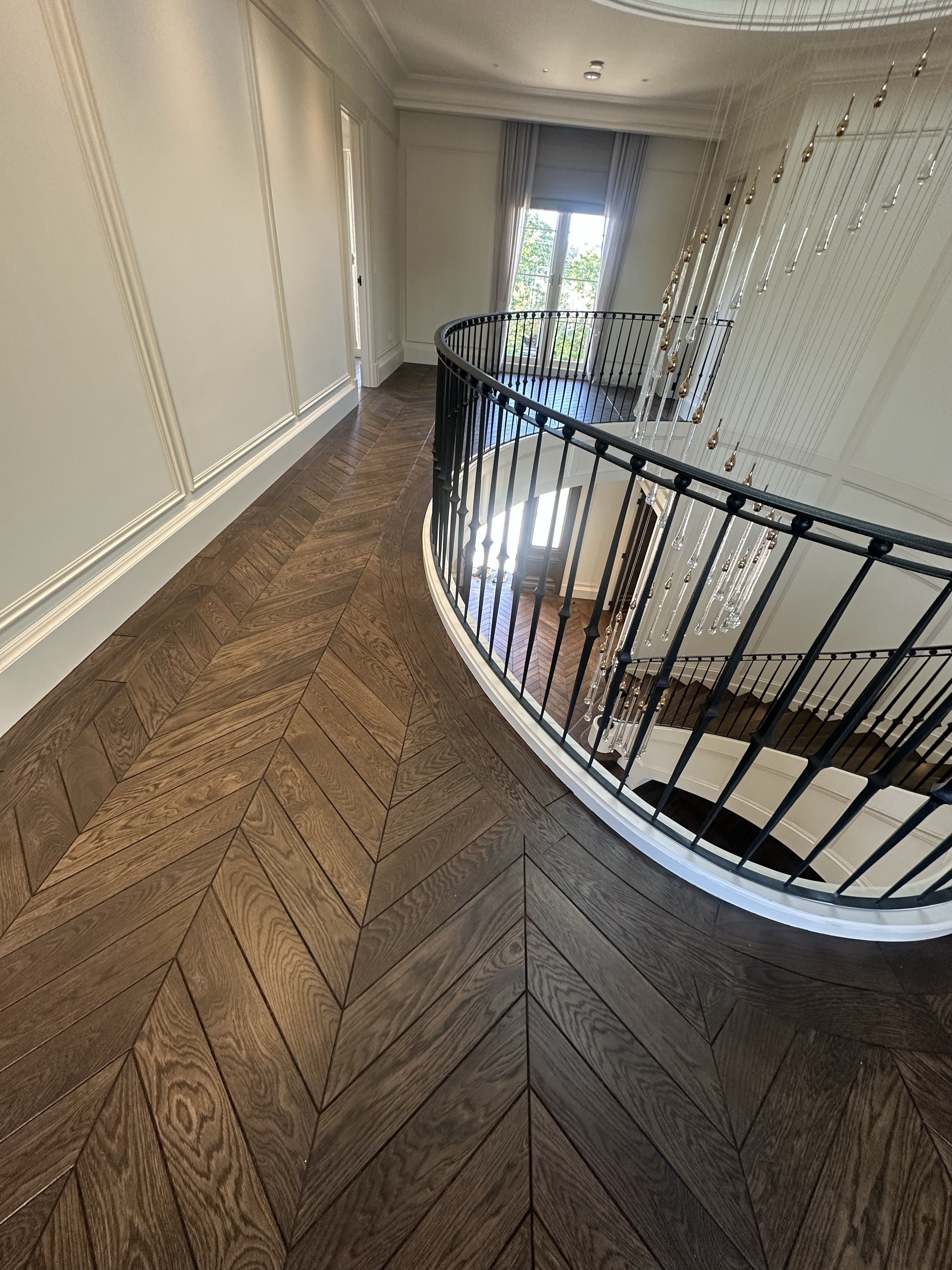 Solid European oak chevron flooring around a curved upper landing.