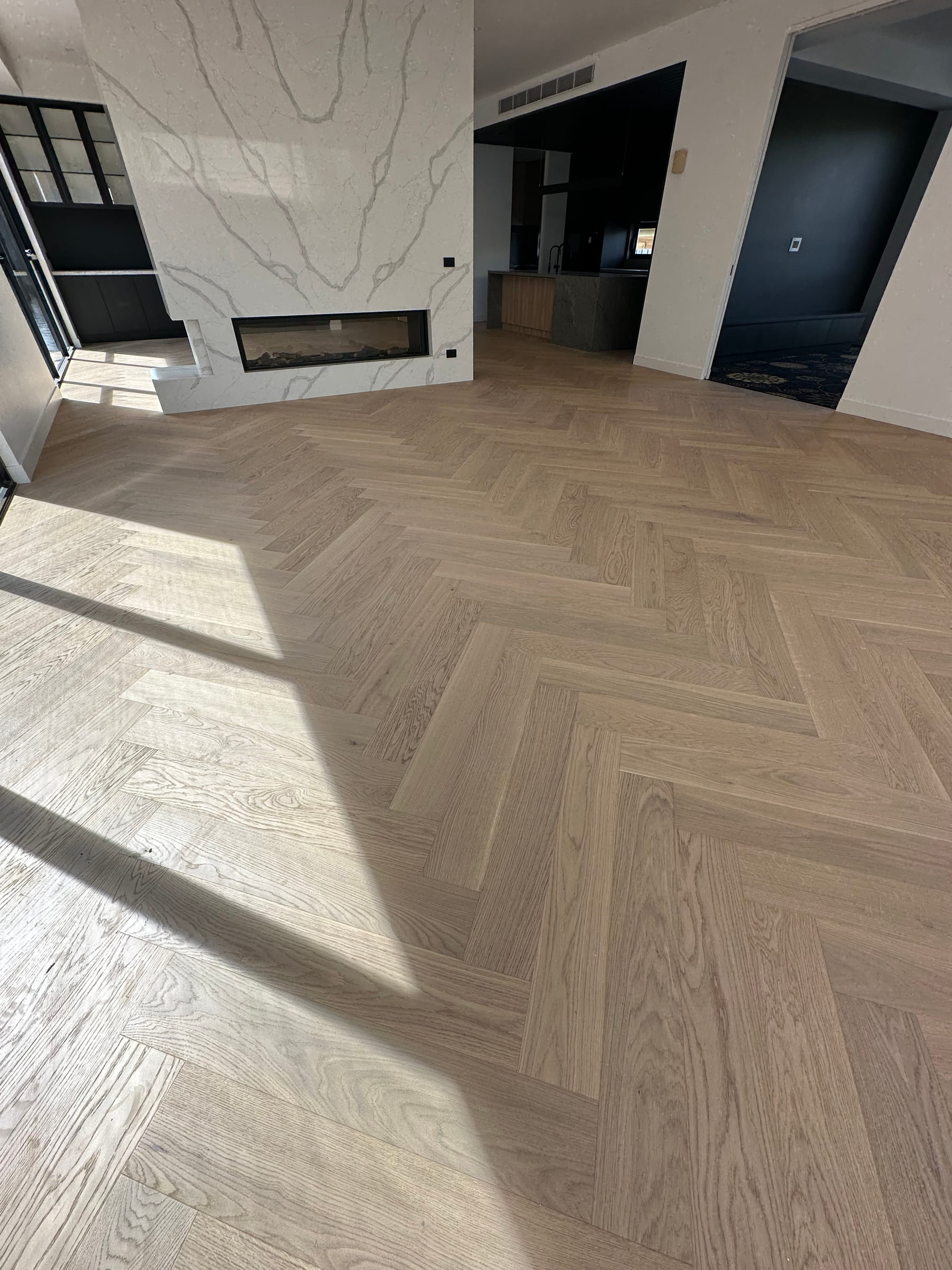 Herringbone oak flooring and fireplace detail in a bright Camberwell living room.