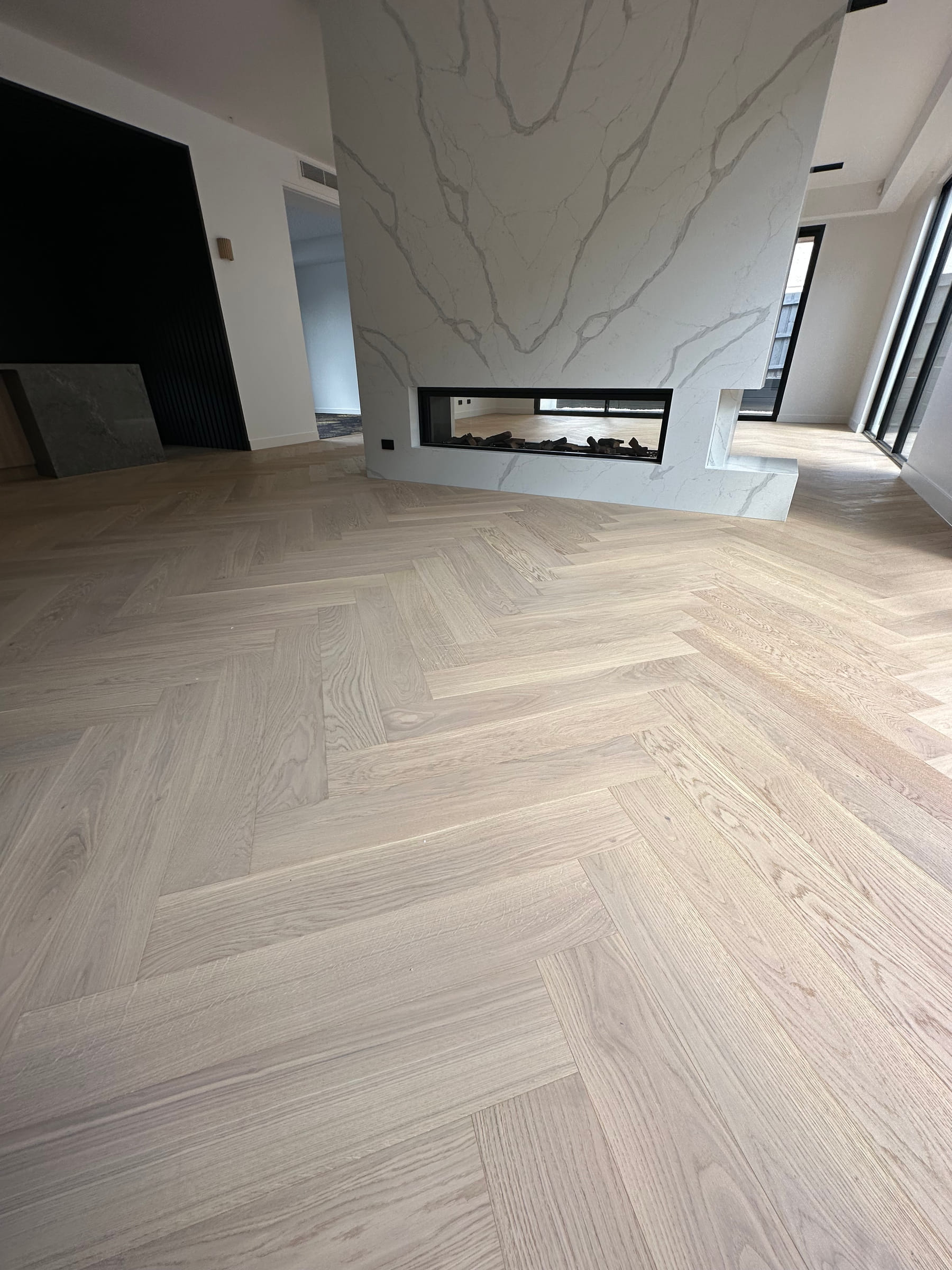 AB-grade herringbone oak flooring laid around a stone fireplace in Camberwell.