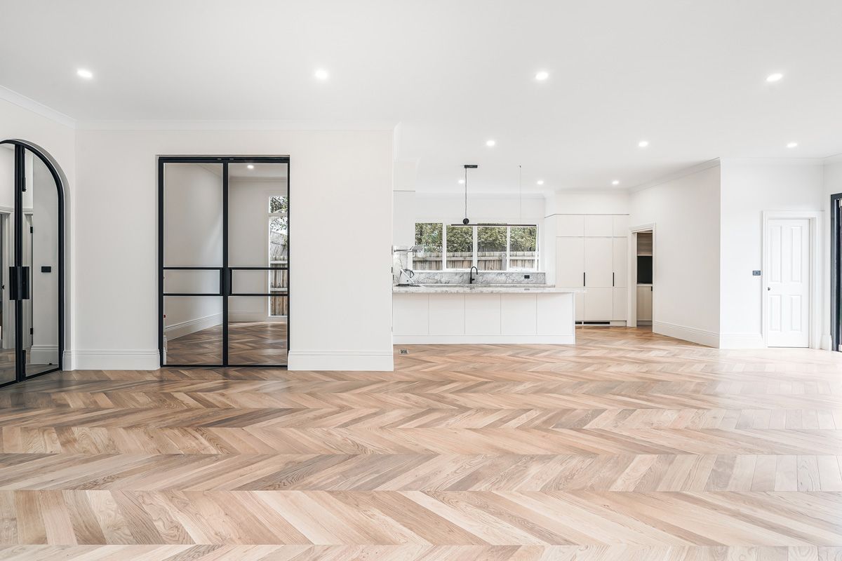 Champagne chevron oak flooring through an open-plan Kew kitchen and living area.