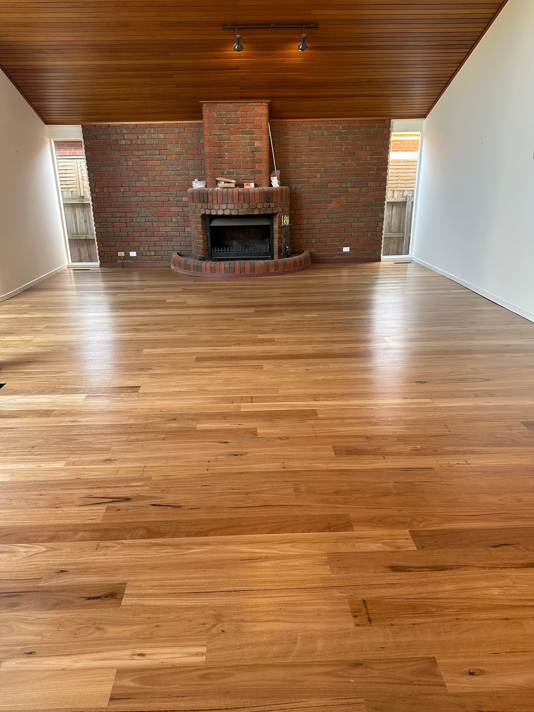 Sanded and polished Blackbutt flooring leading to the brick fireplace in a Malvern living area.