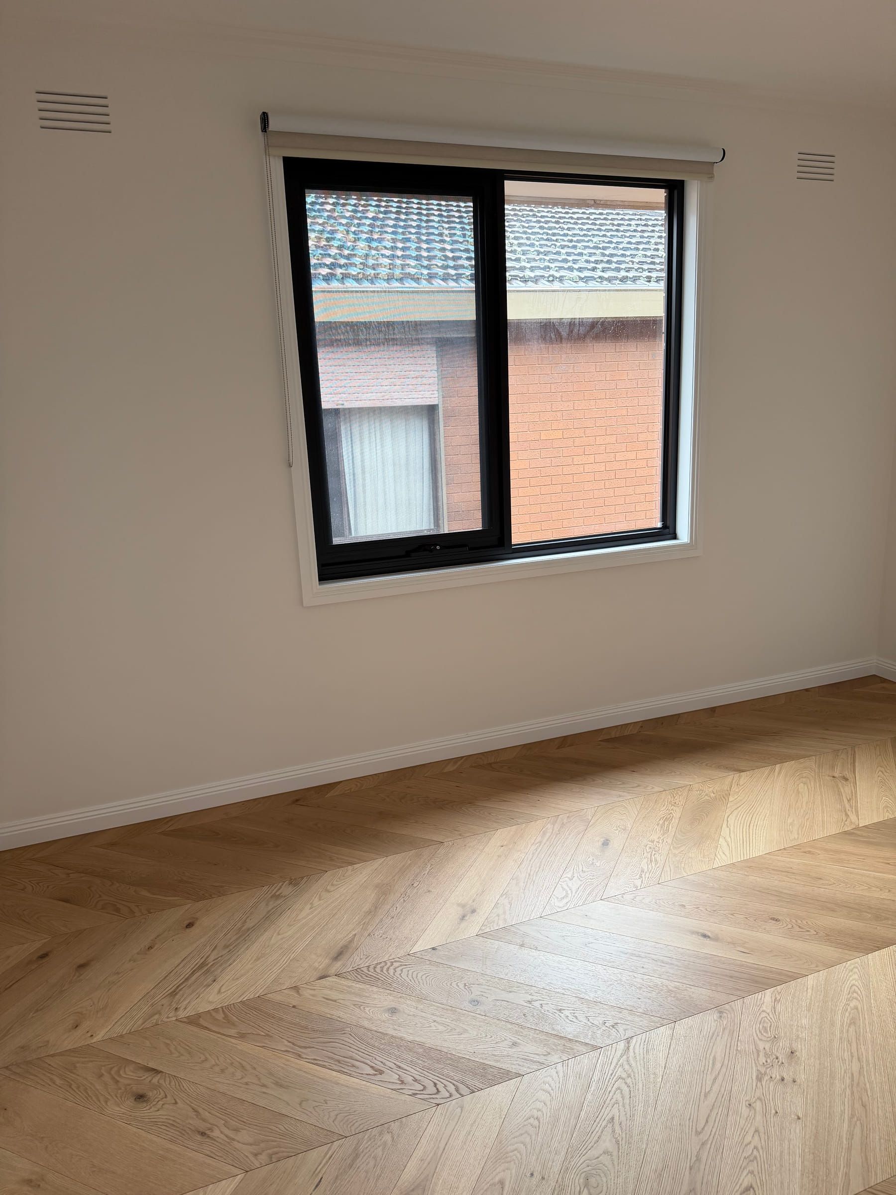 Natural Oak chevron flooring across a sunlit bedroom with a black-framed window in Bulleen.