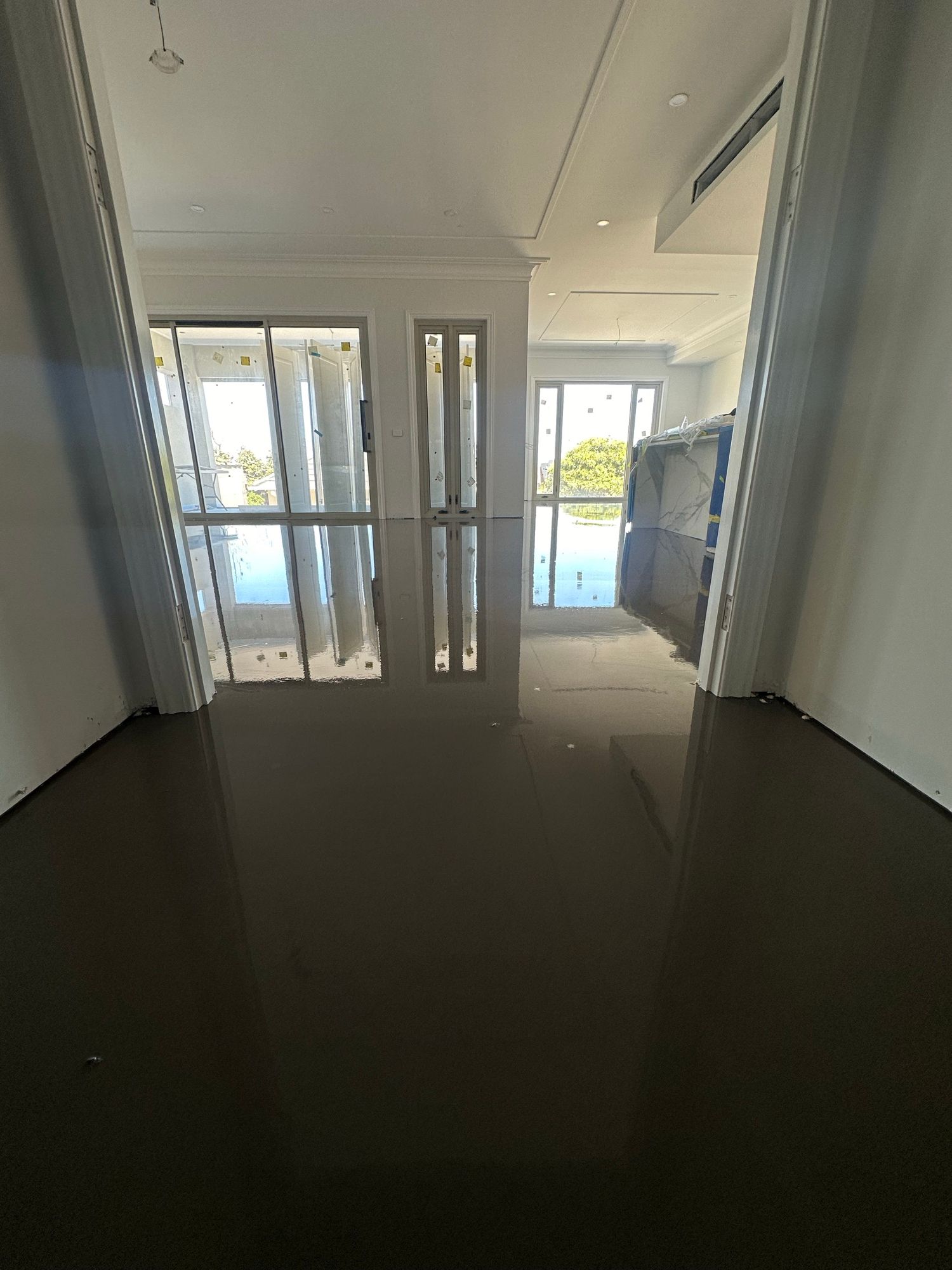 Freshly completed wet self-levelling layer extending through connected rooms of a residential home.