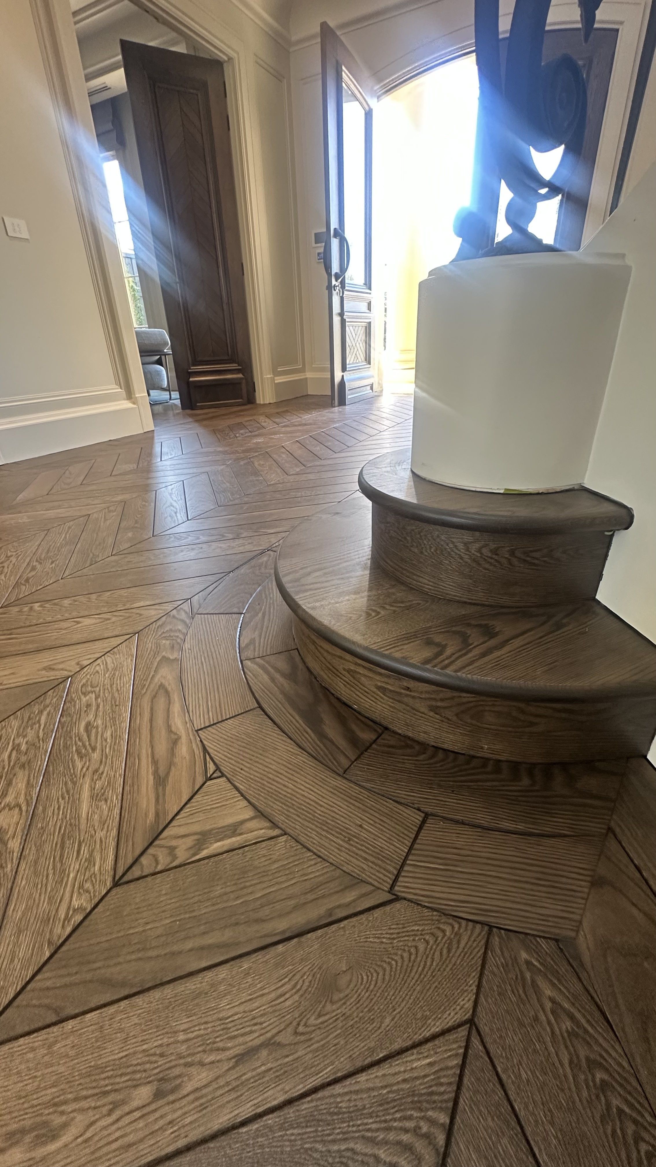 Solid European oak chevron flooring around a curved staircase column.