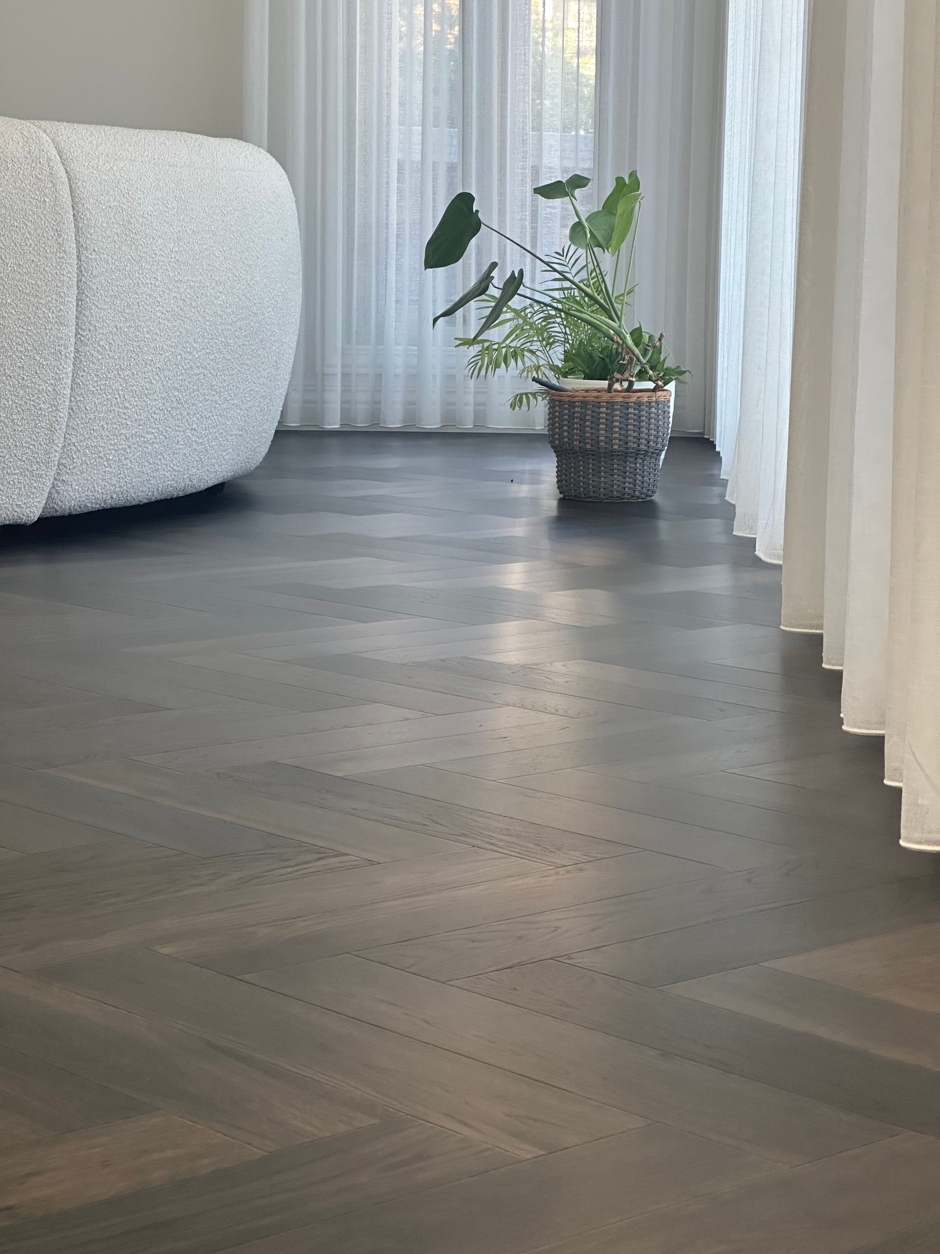 Ash Grey herringbone flooring beside a curved sofa in a Camberwell living room.
