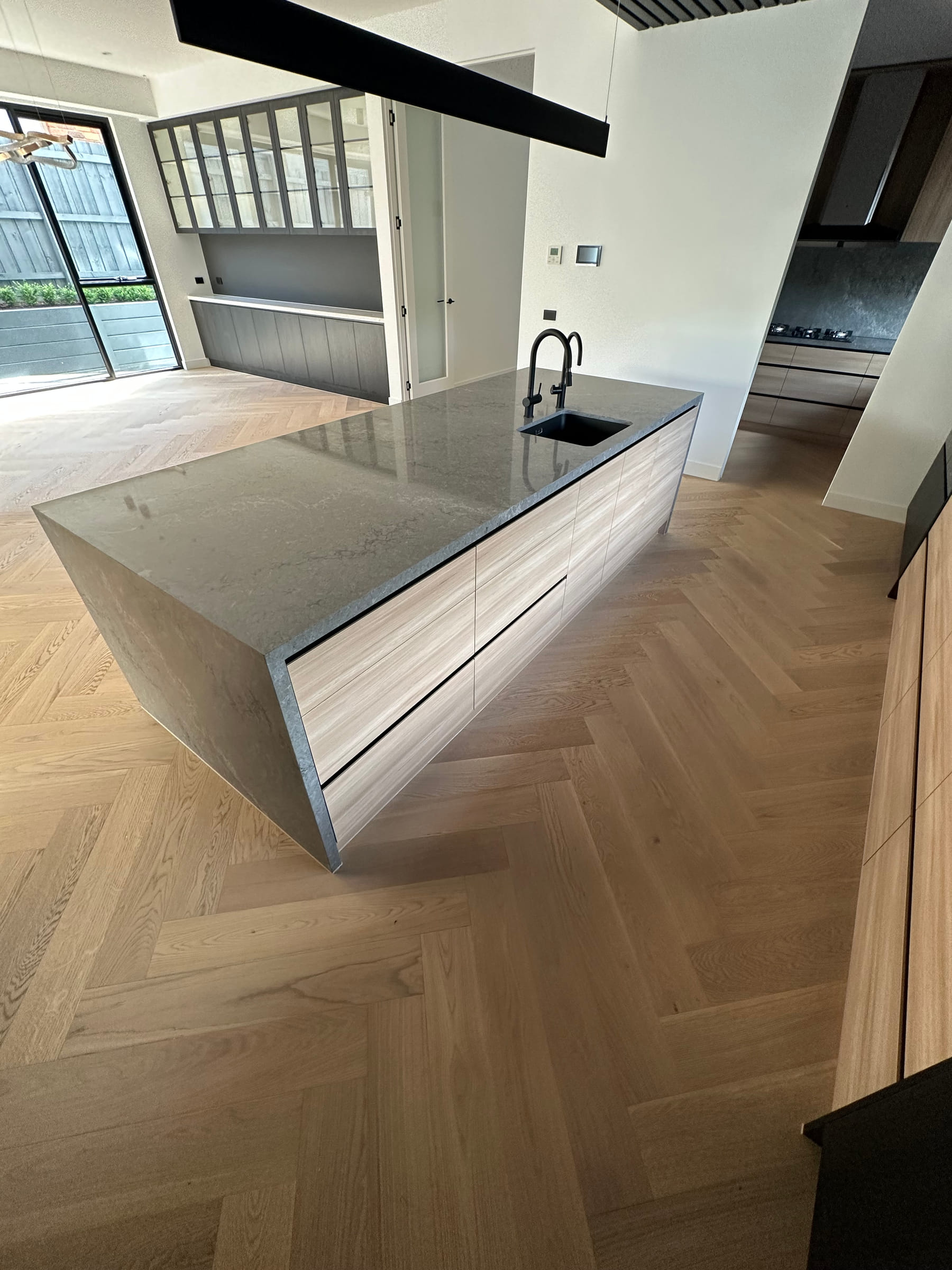Oak herringbone pattern aligned around a Camberwell kitchen island and cabinetry.