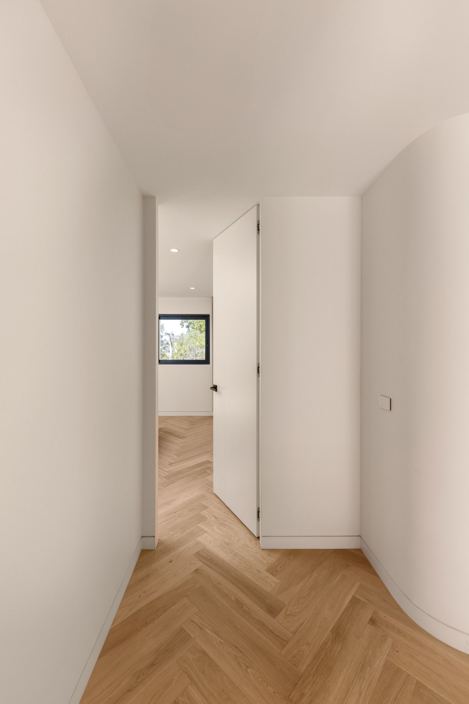 Natural Oak herringbone flooring aligned through a curved Kew corridor.