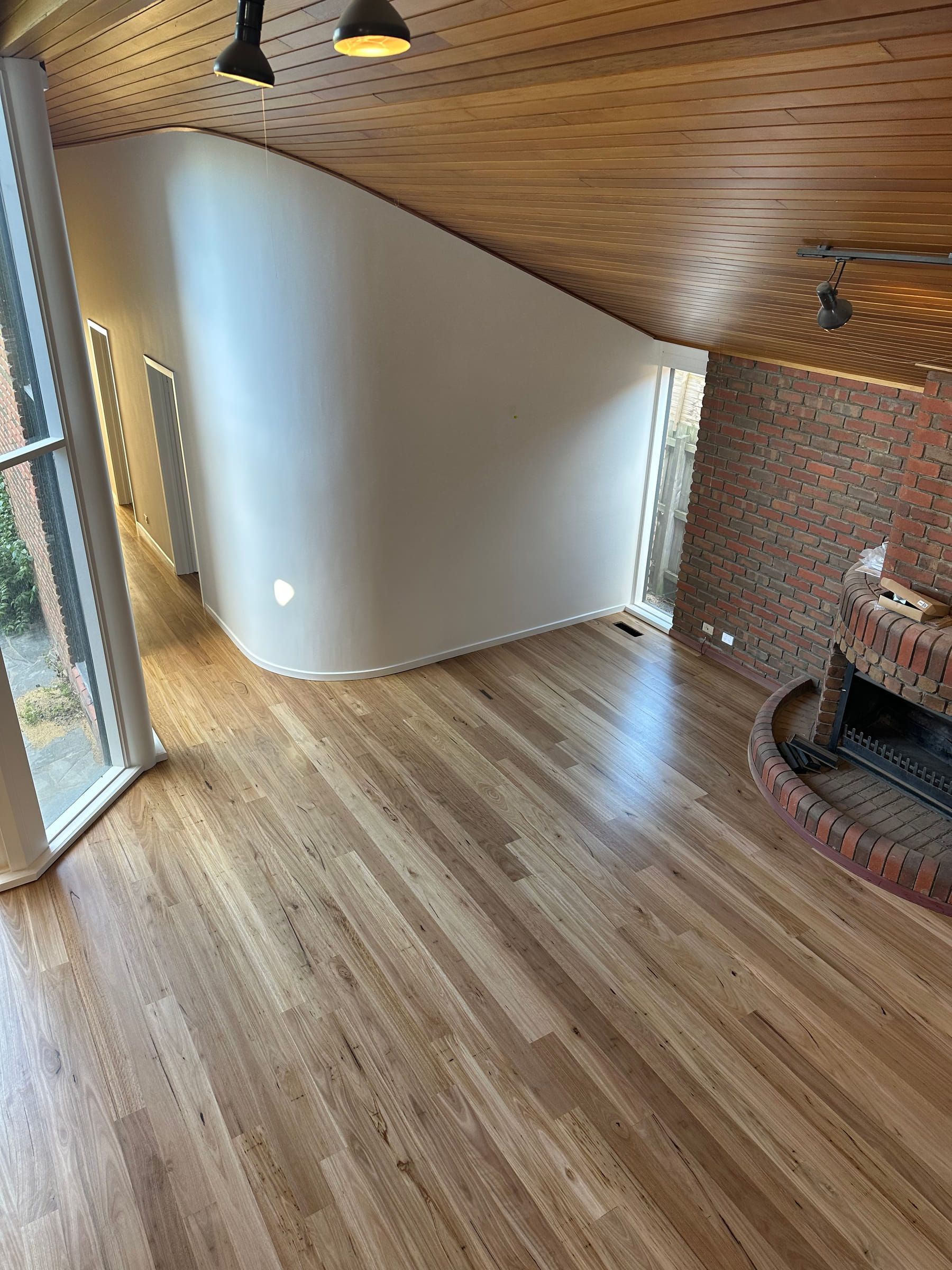 Solid Blackbutt flooring beside a curved internal wall and brick fireplace in Malvern.