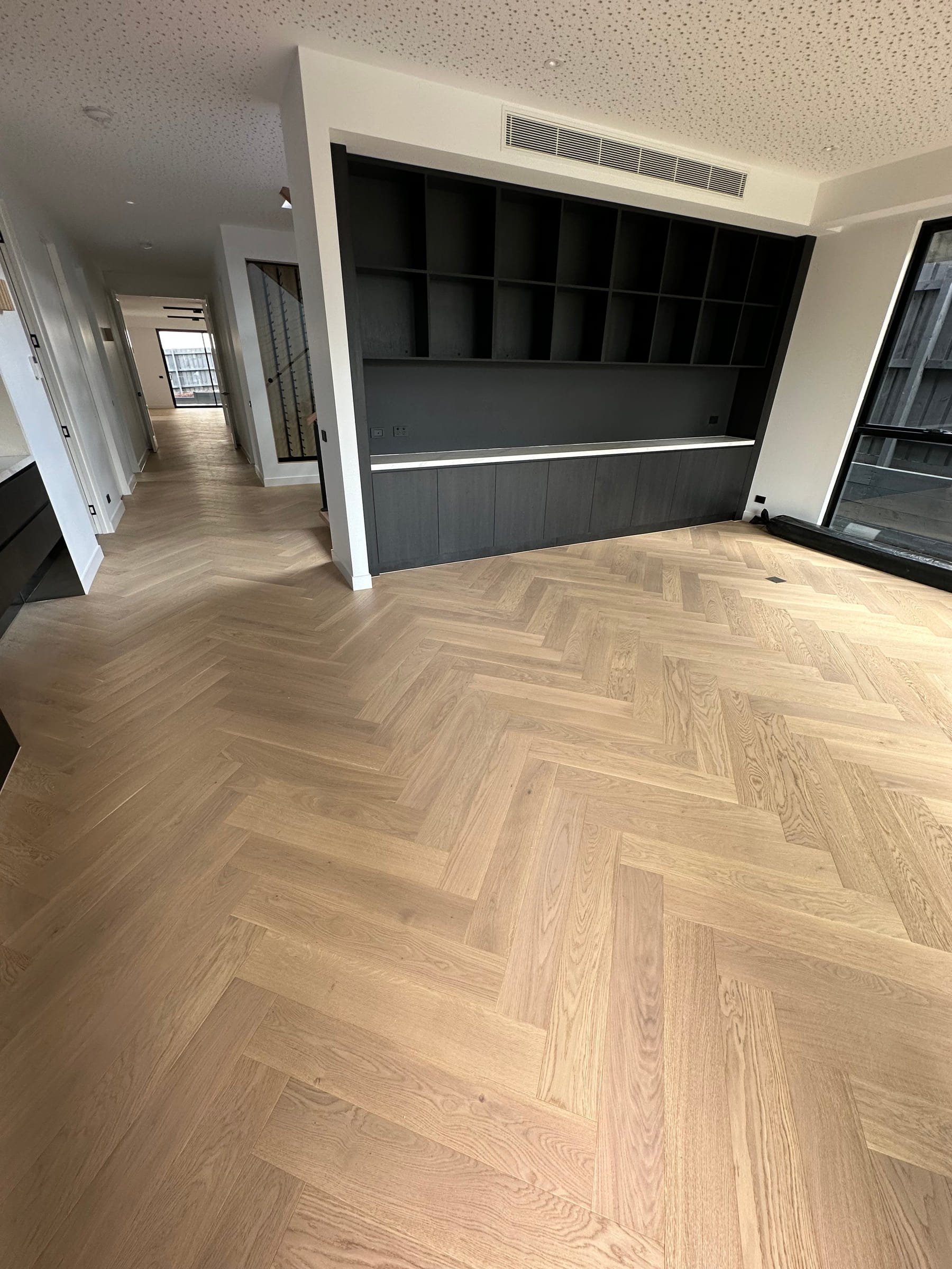 Natural oak herringbone flooring in a Camberwell room with dark built-in cabinetry.