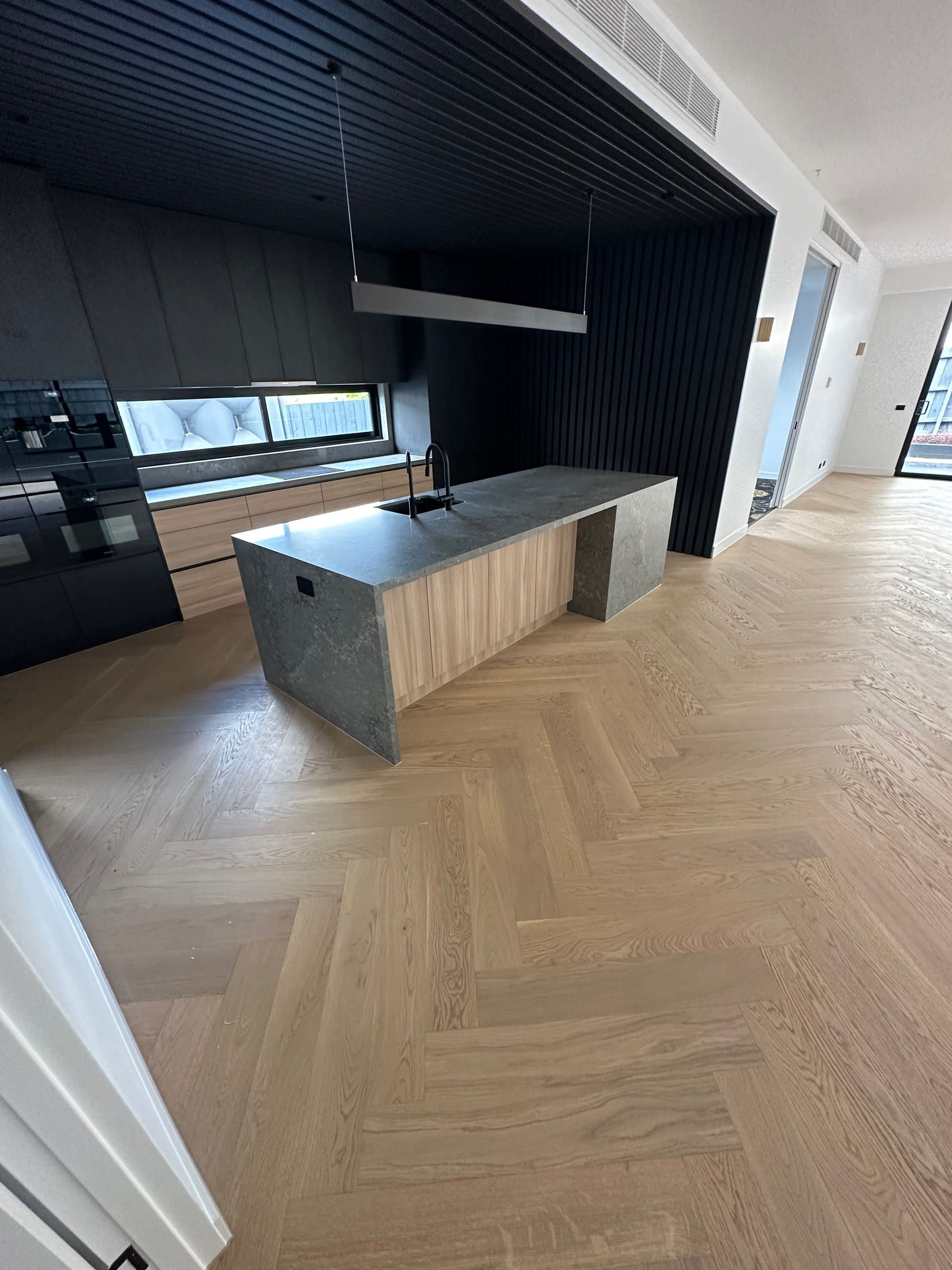 Engineered oak herringbone flooring at the entrance to a dark Camberwell kitchen.