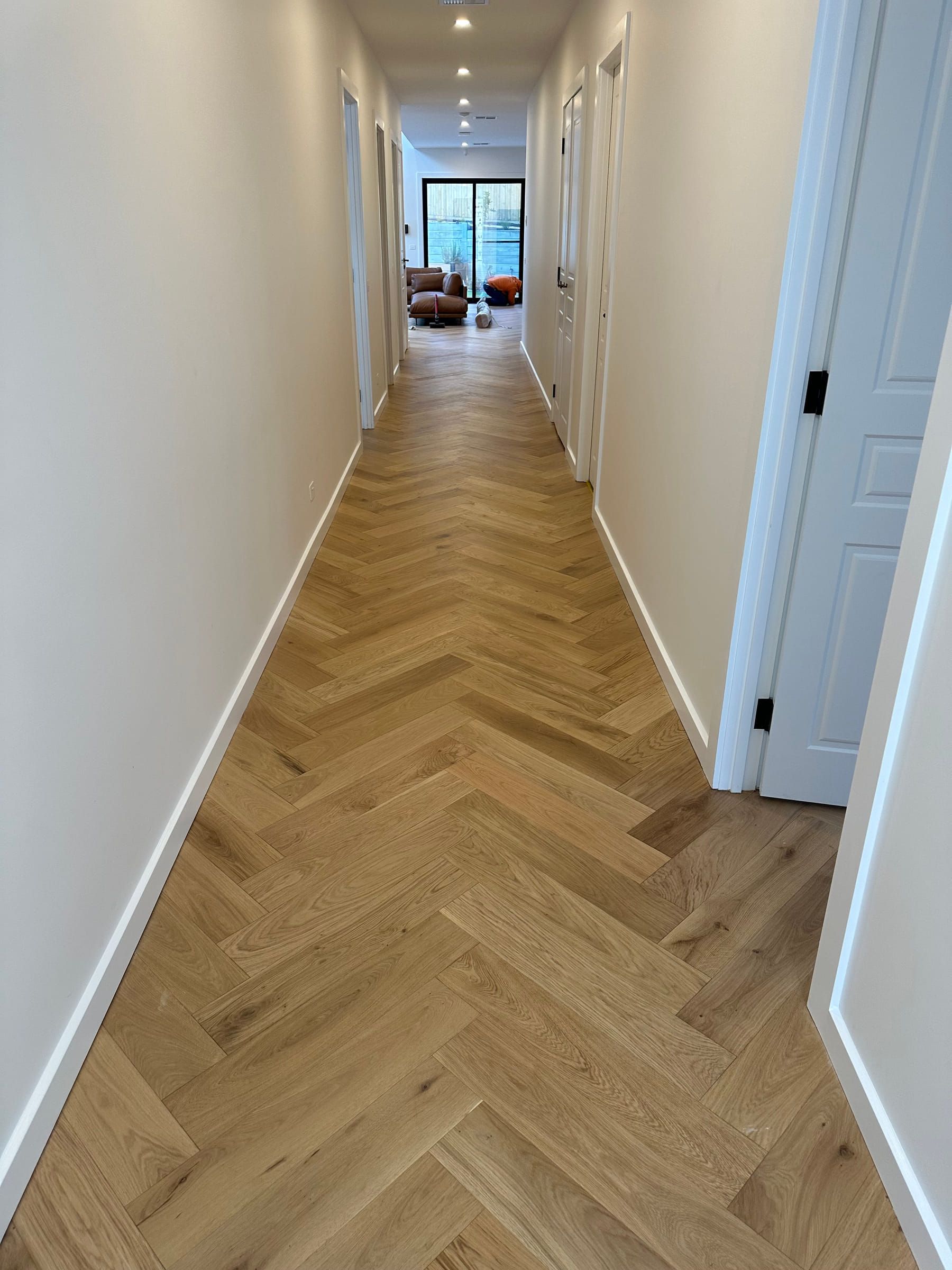 Natural oak herringbone flooring aligned along a long Canterbury hallway.
