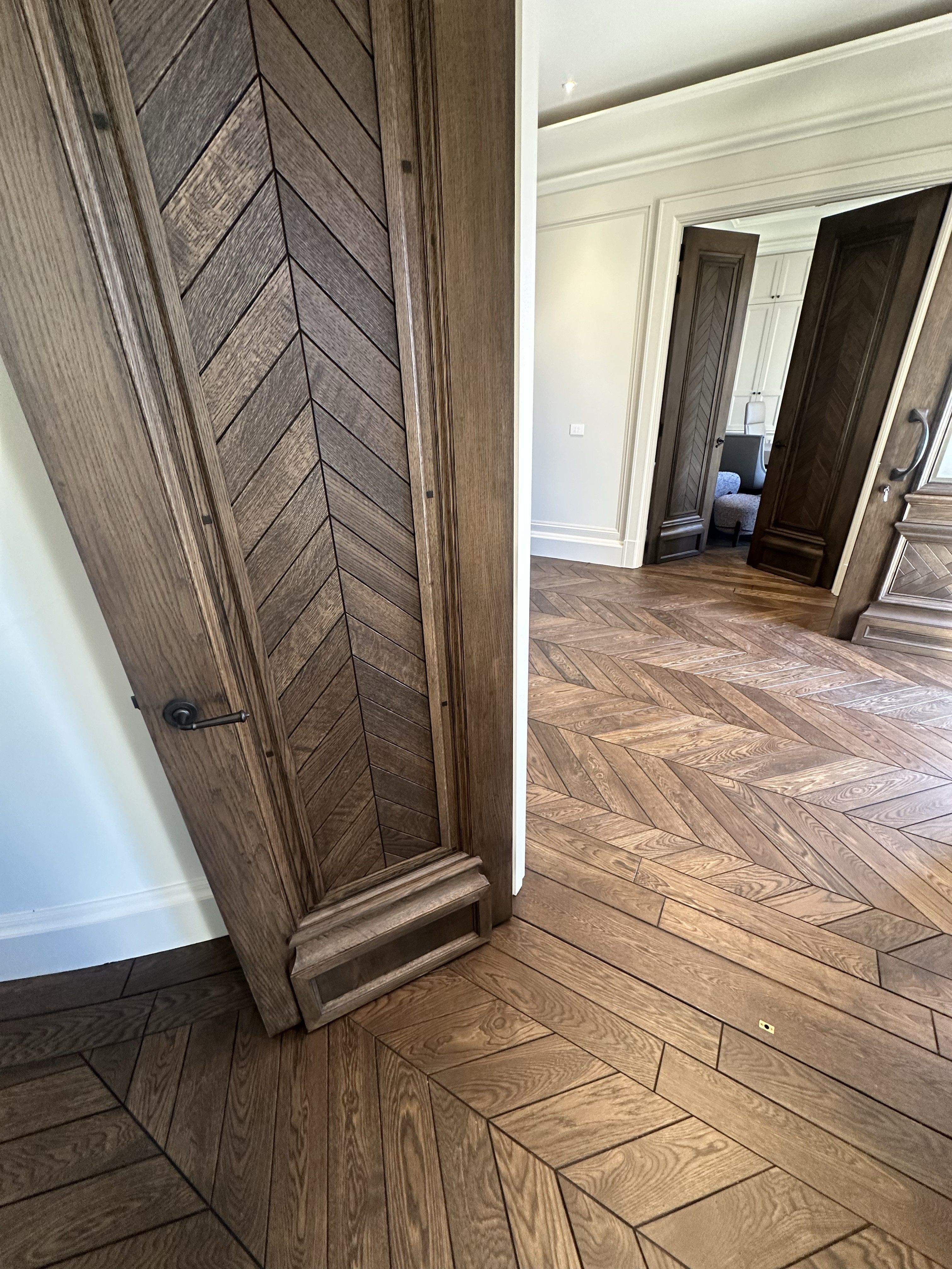 Solid oak chevron flooring continuing through a detailed timber doorway.