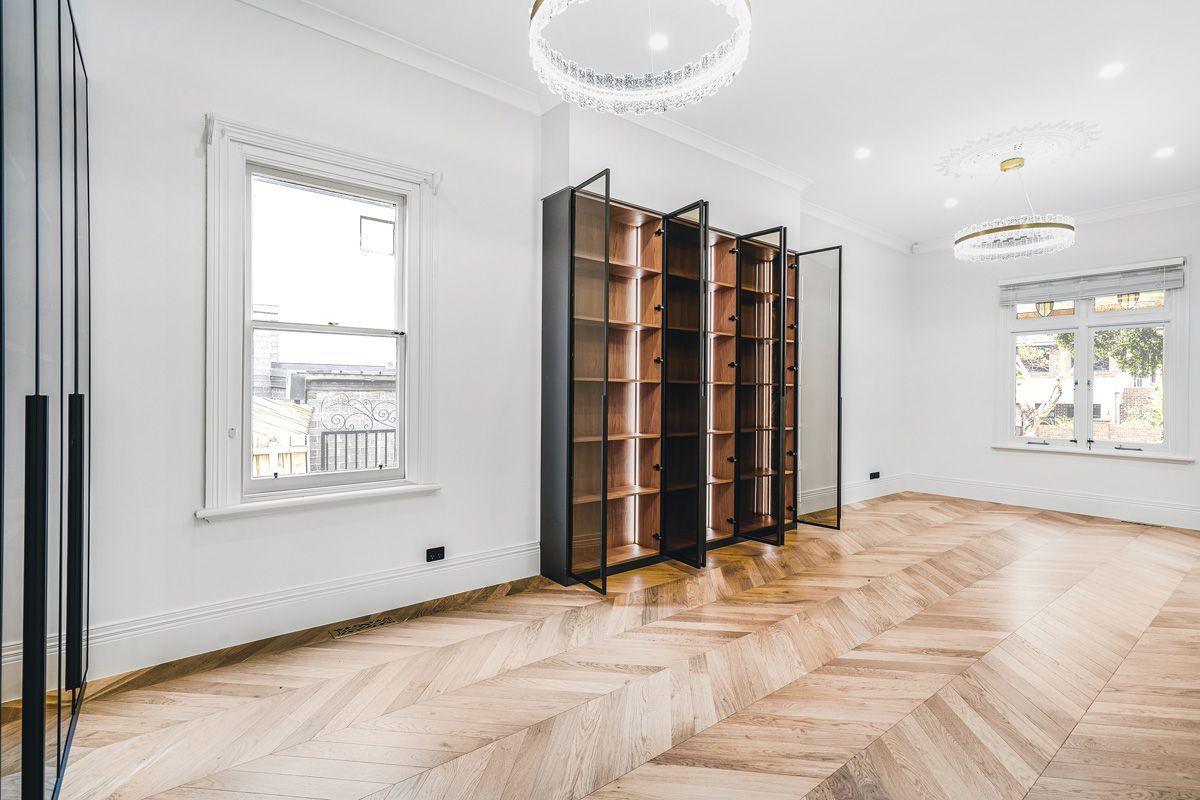 Champagne chevron oak flooring across a large Kew library and living space.