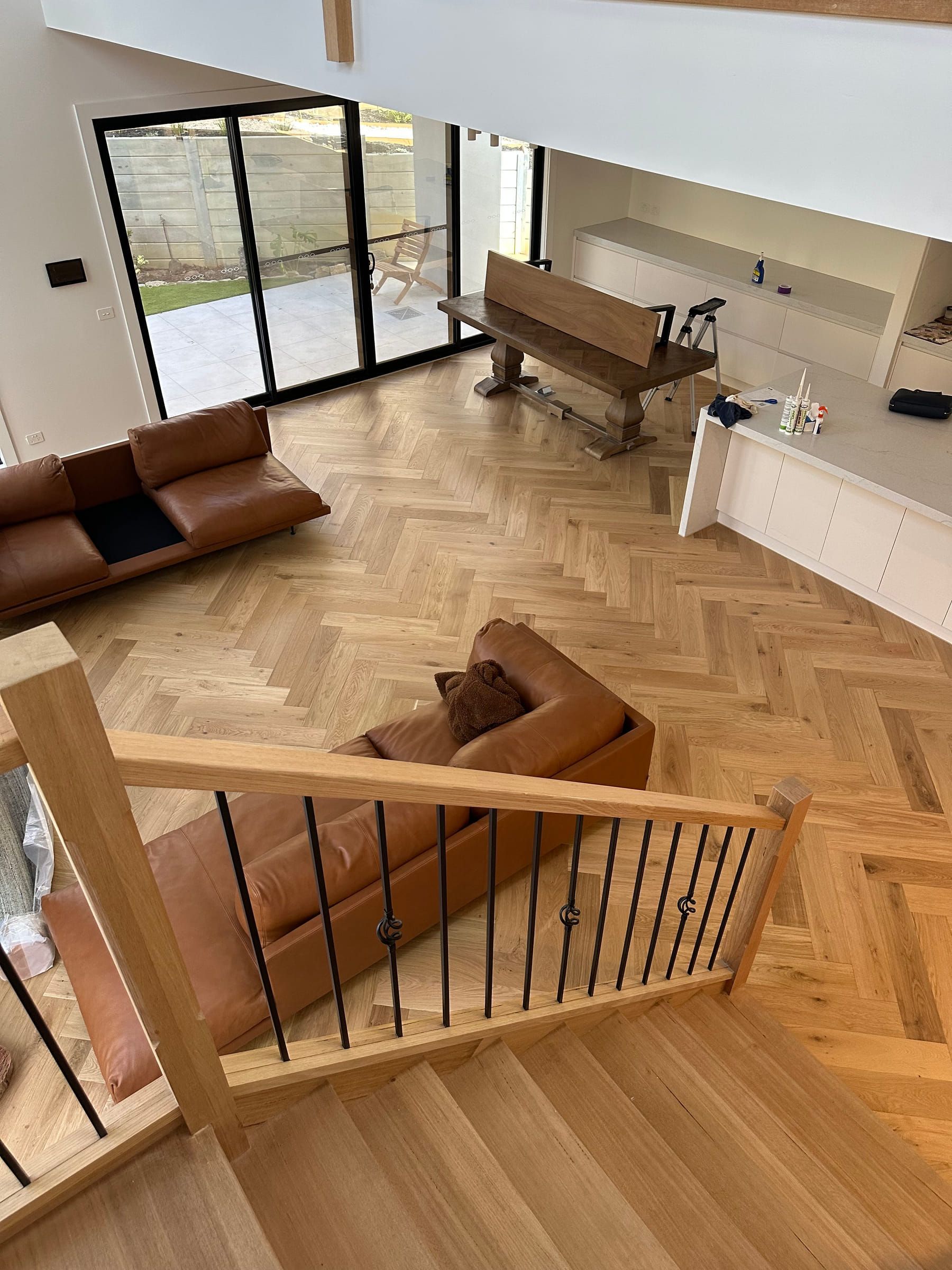 Natural oak herringbone flooring between a Canterbury staircase, kitchen and living room.