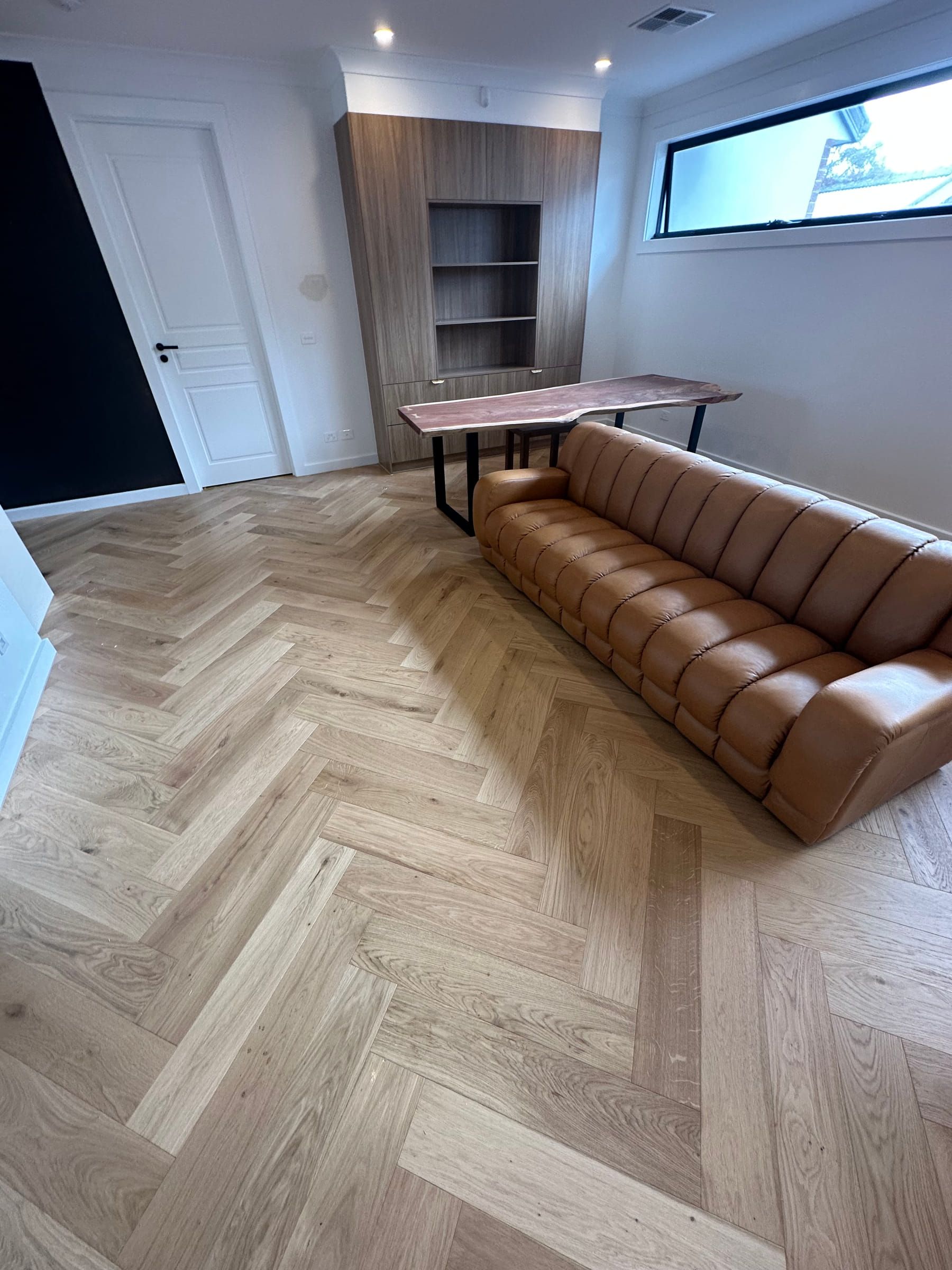 GrandOak Natural Oak herringbone flooring beside a leather sofa in Canterbury.