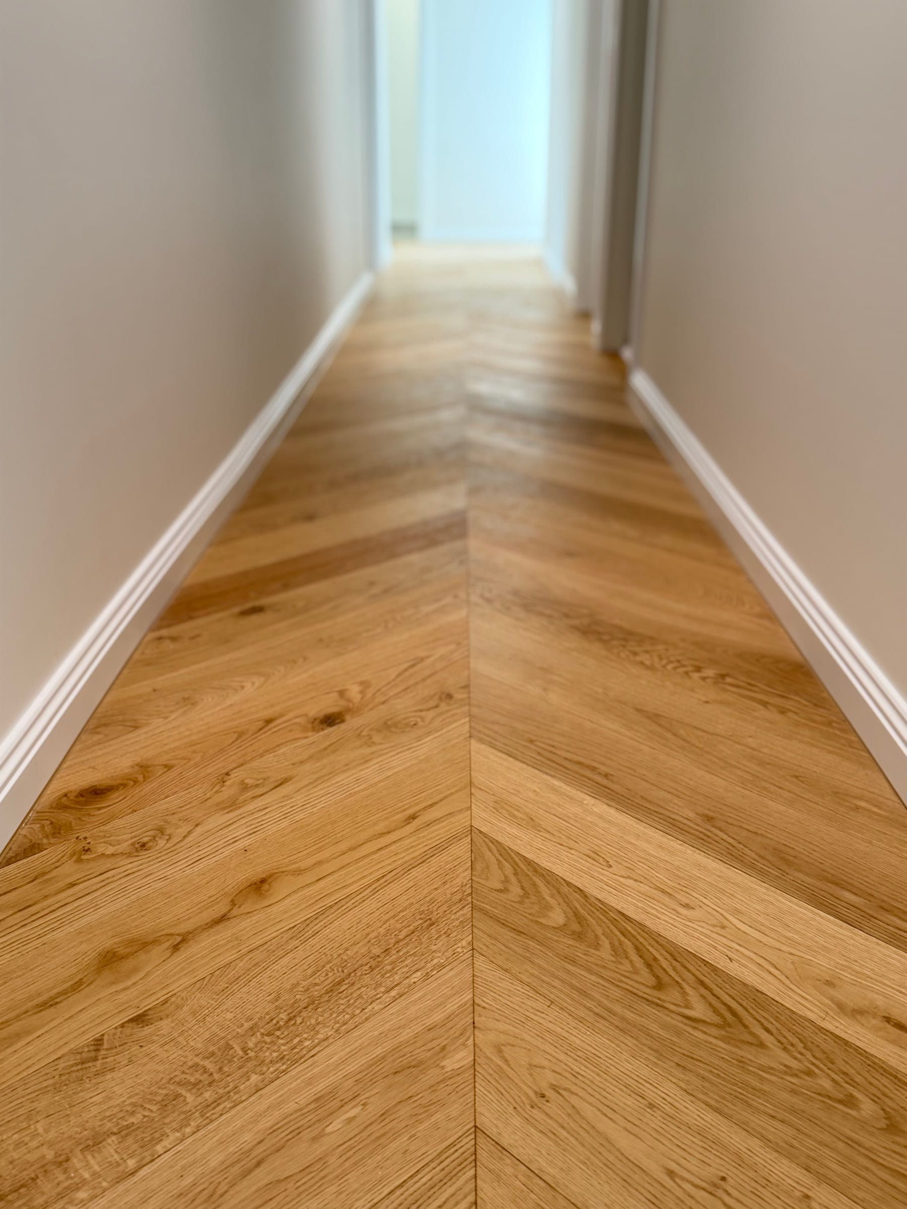 Low-angle view along the centre line of the Natural Oak chevron hallway in Bulleen.
