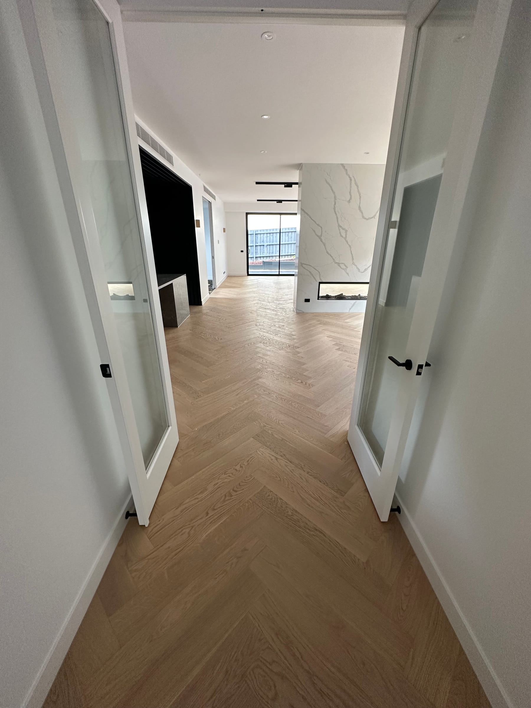 Herringbone flooring continuing through a Camberwell hallway towards the living area.