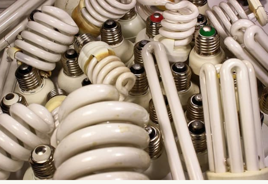 A pile of various used compact fluorescent light bulbs.