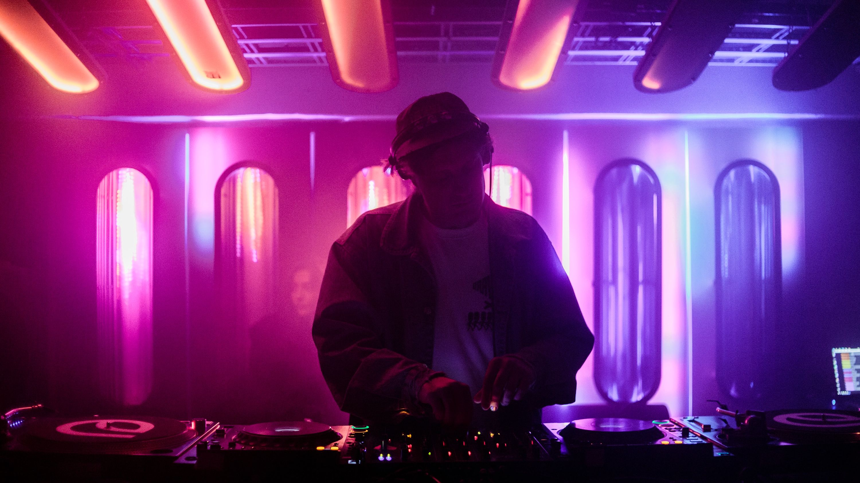 a dj is playing music in a dark room with purple lights .