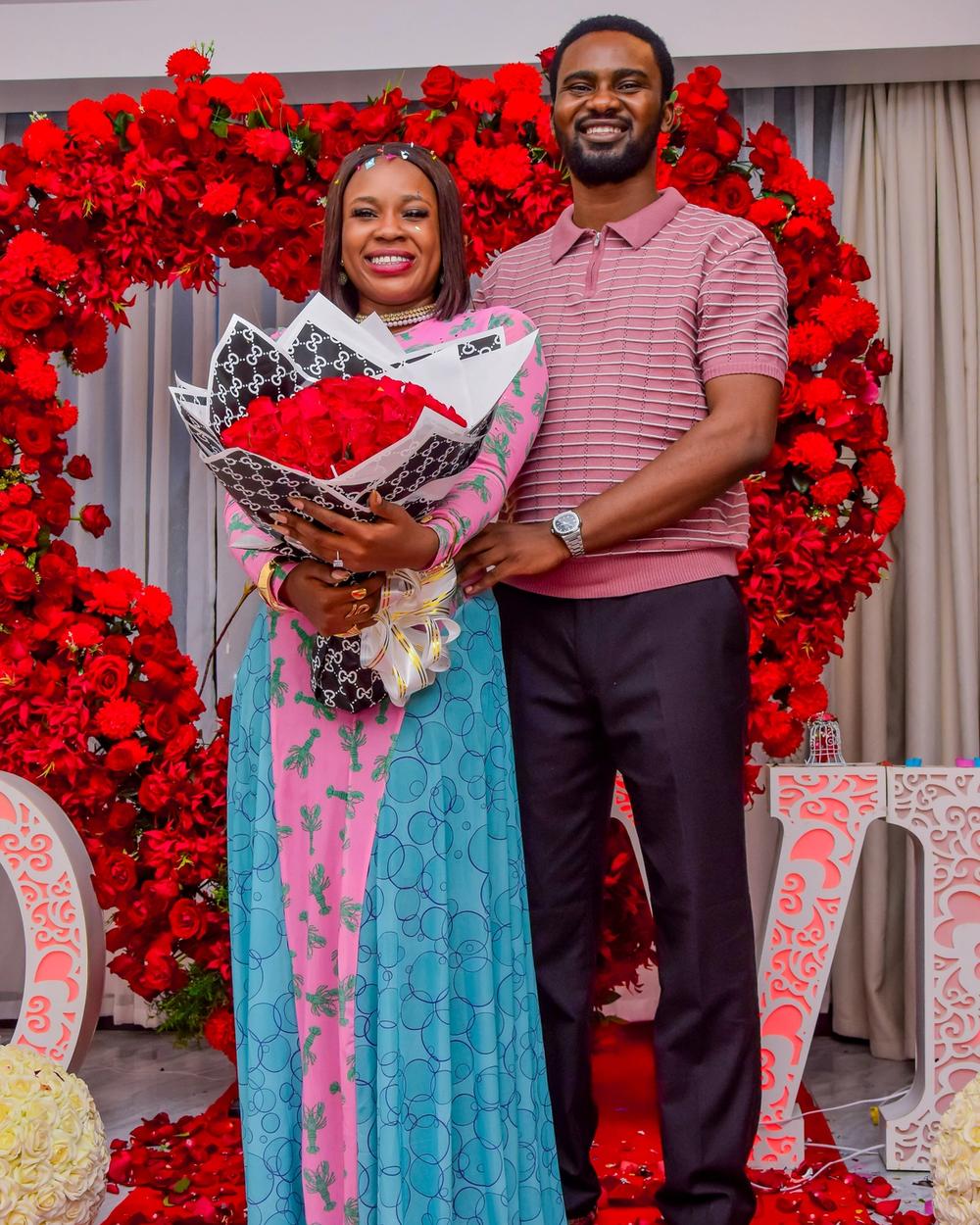 Newly engaged couple smiling together in front of the rose arch