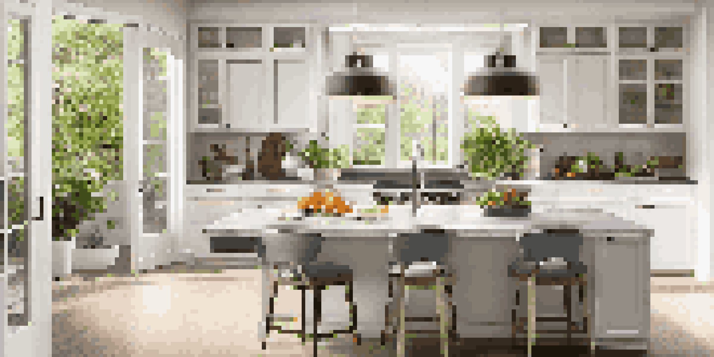 A modern kitchen with white cabinets, marble countertop, and natural light shining through a window.