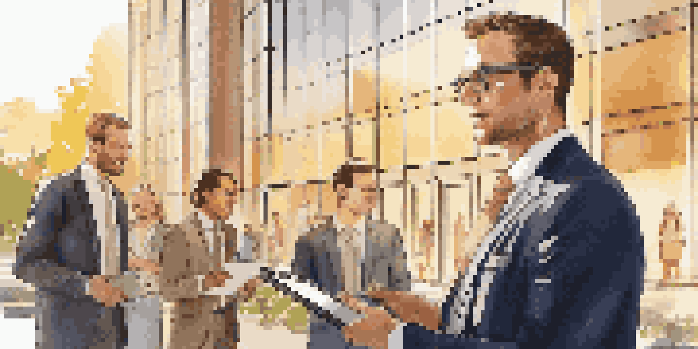 A real estate agent in a suit stands in front of a modern building, engaging with smiling clients during golden hour.
