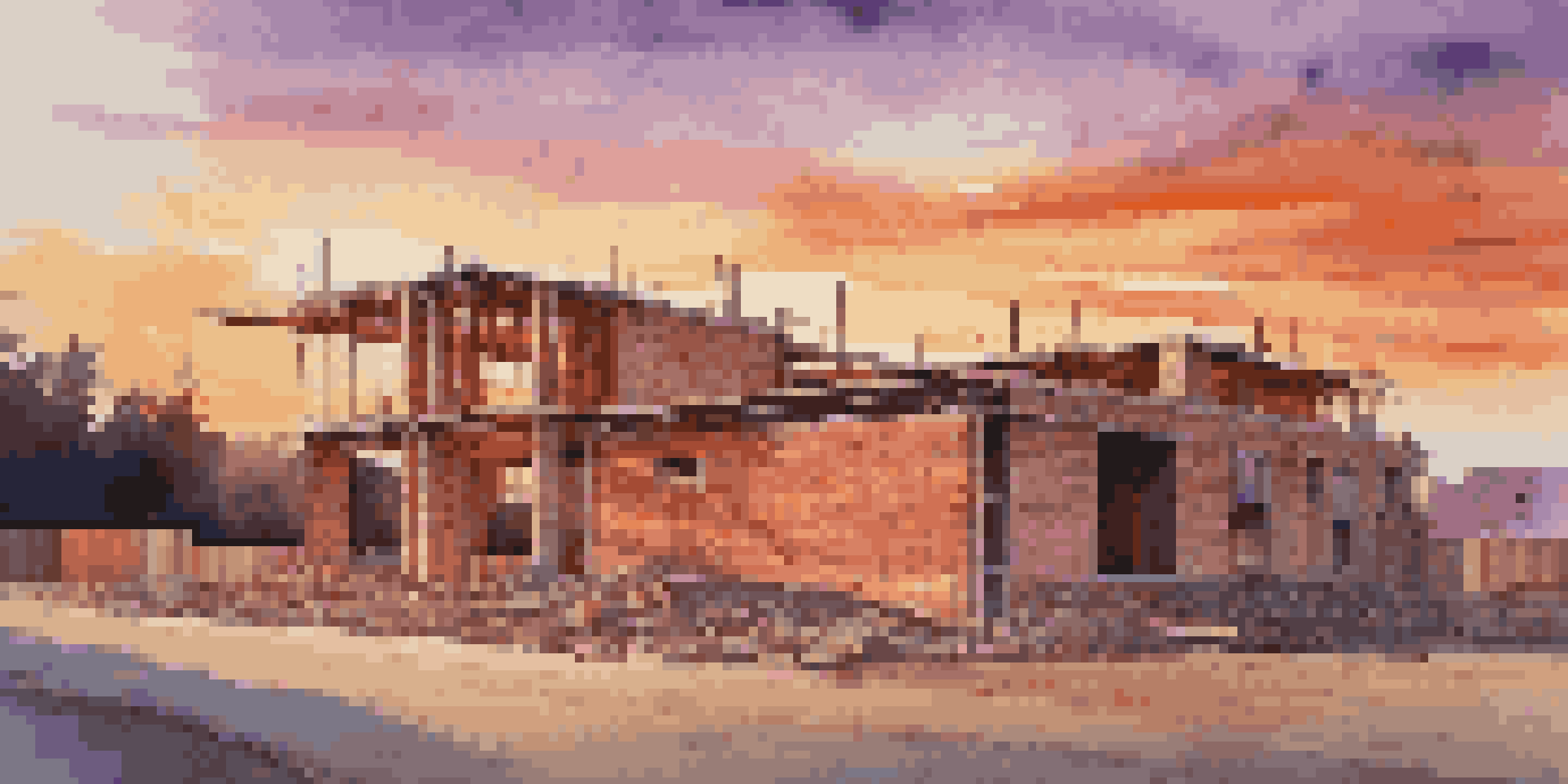 A modern residential construction site with a partially completed house, surrounded by construction materials under a colorful sunset sky.