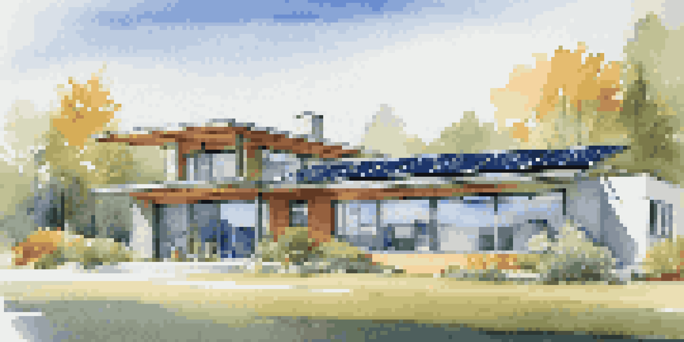 A modern home with large energy-efficient windows, a reflective metal roof, and solar panels under a clear blue sky.
